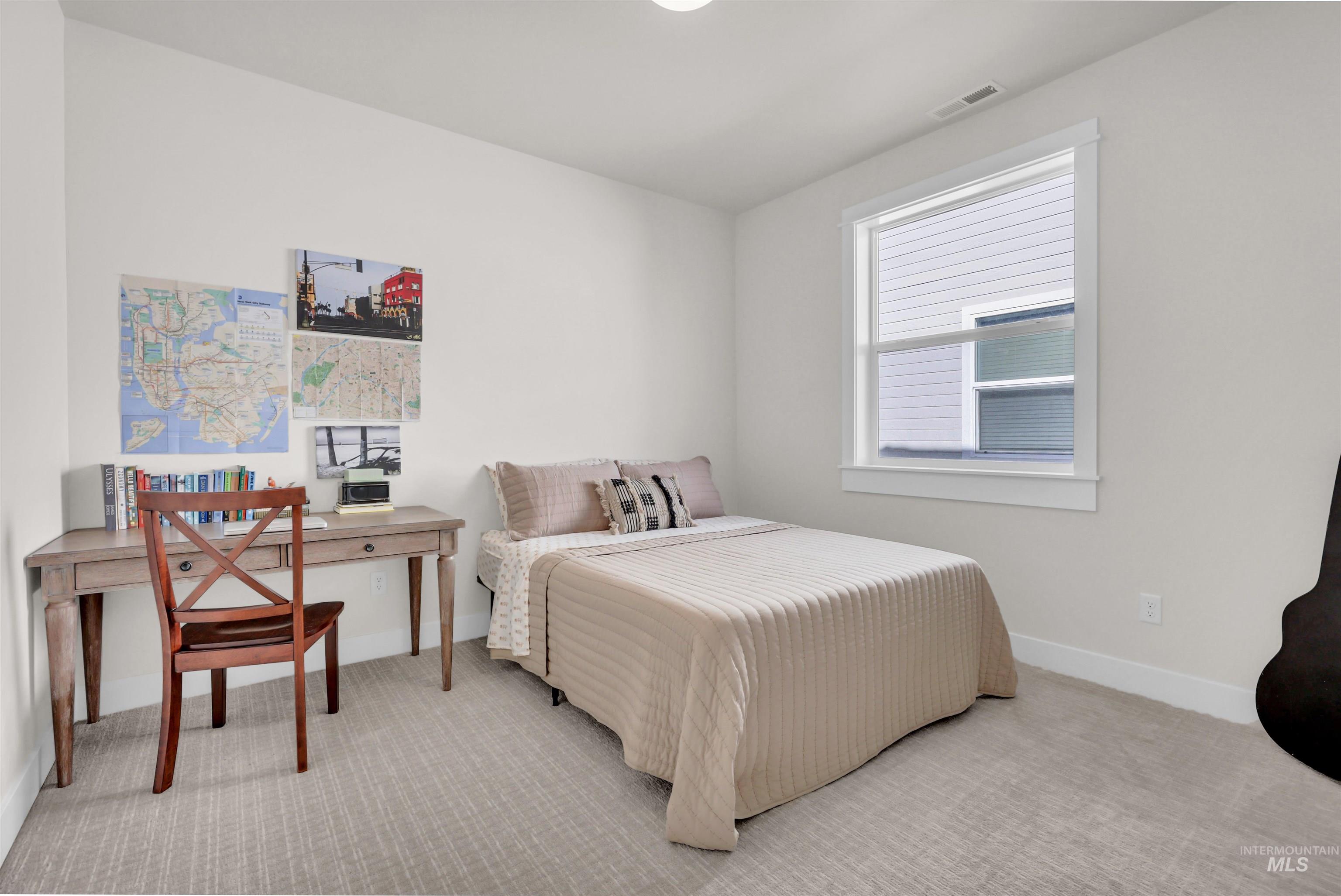 Carpeted bedroom with baseboards and a desk