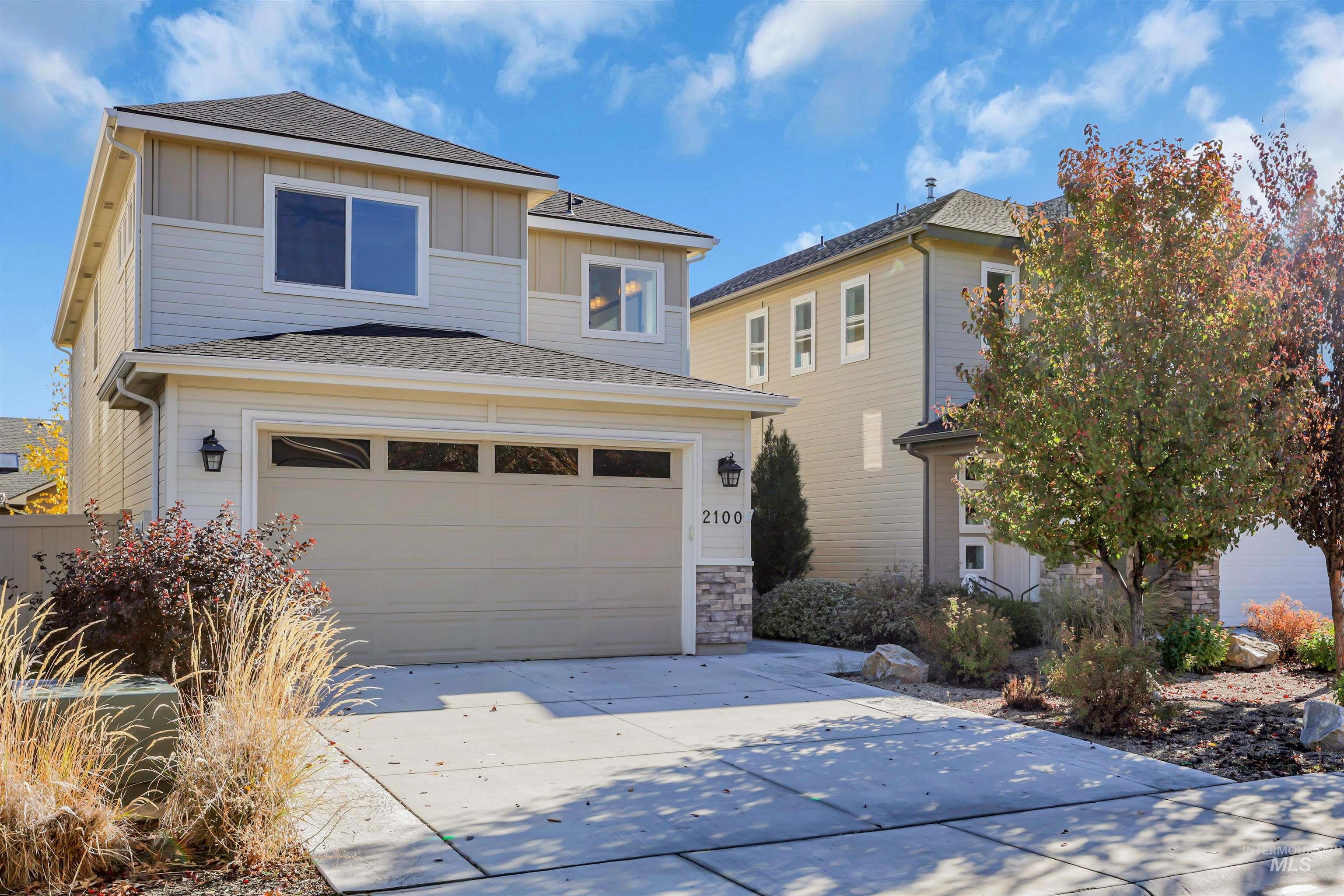 View of front of property featuring board and batten siding, roof with shingles, concrete driveway, and stone siding
