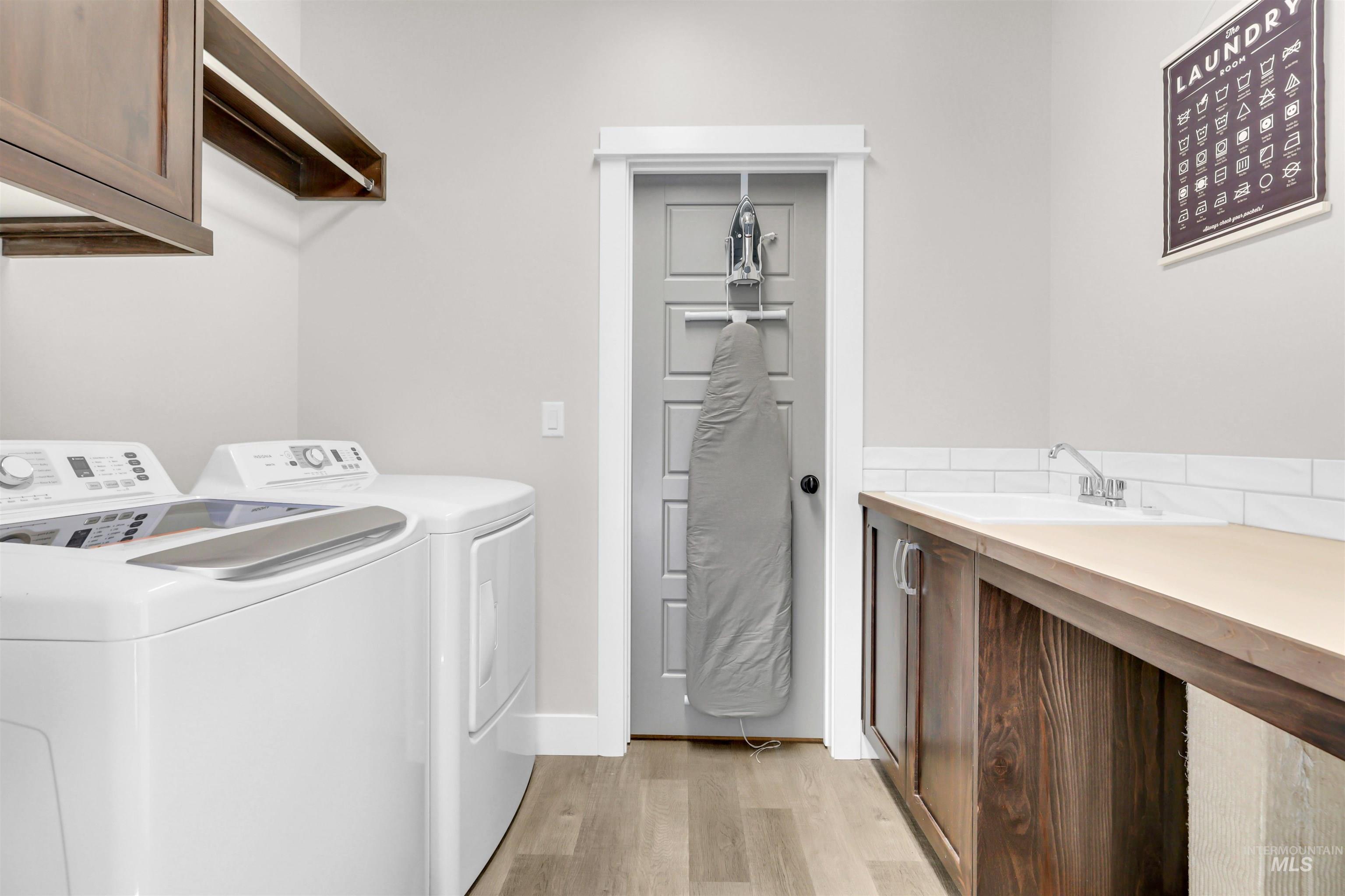 Laundry room with cabinet space, light wood-style floors, and washer and dryer