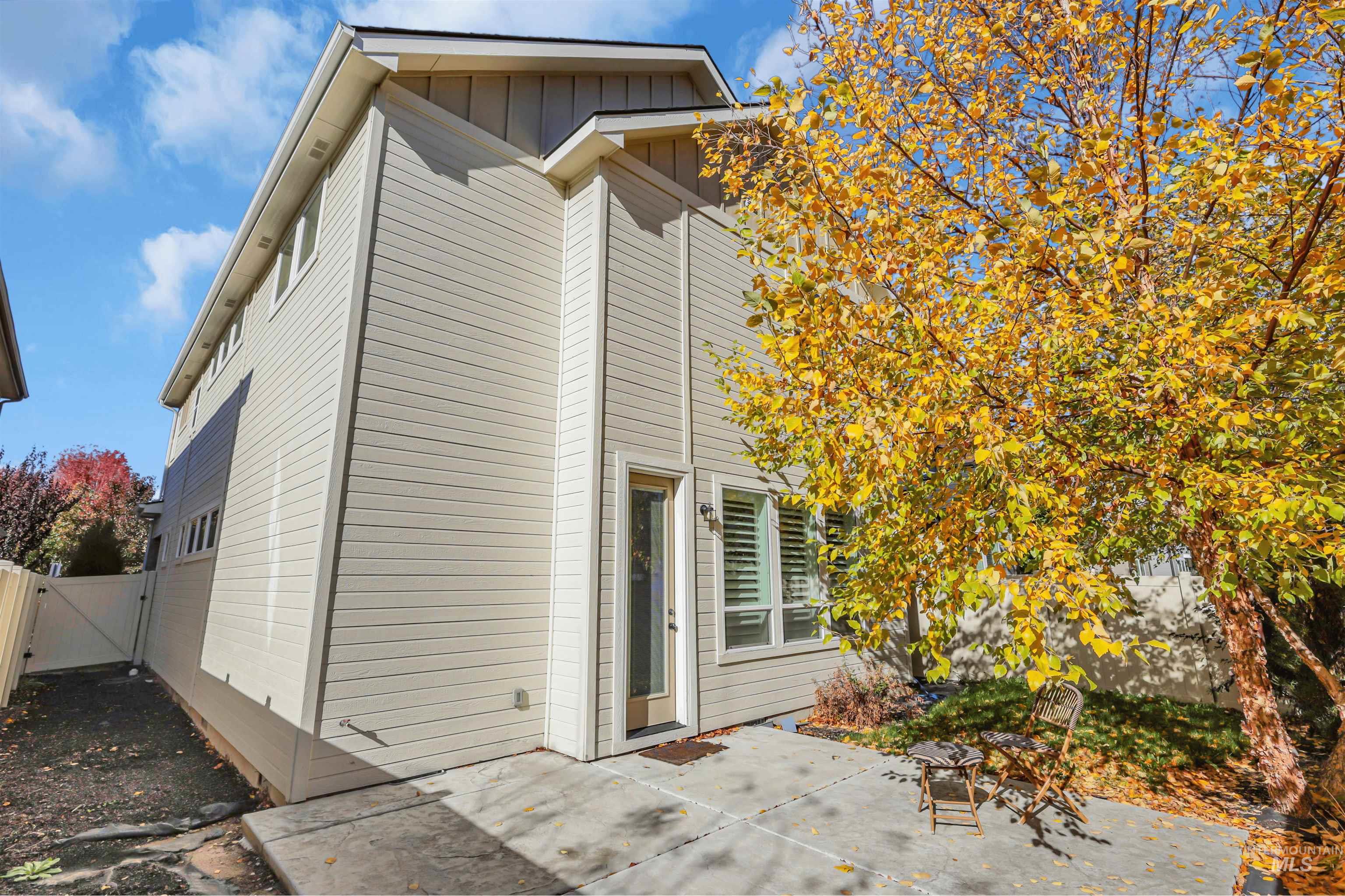 View of side of property with board and batten siding, a patio, and a gate
