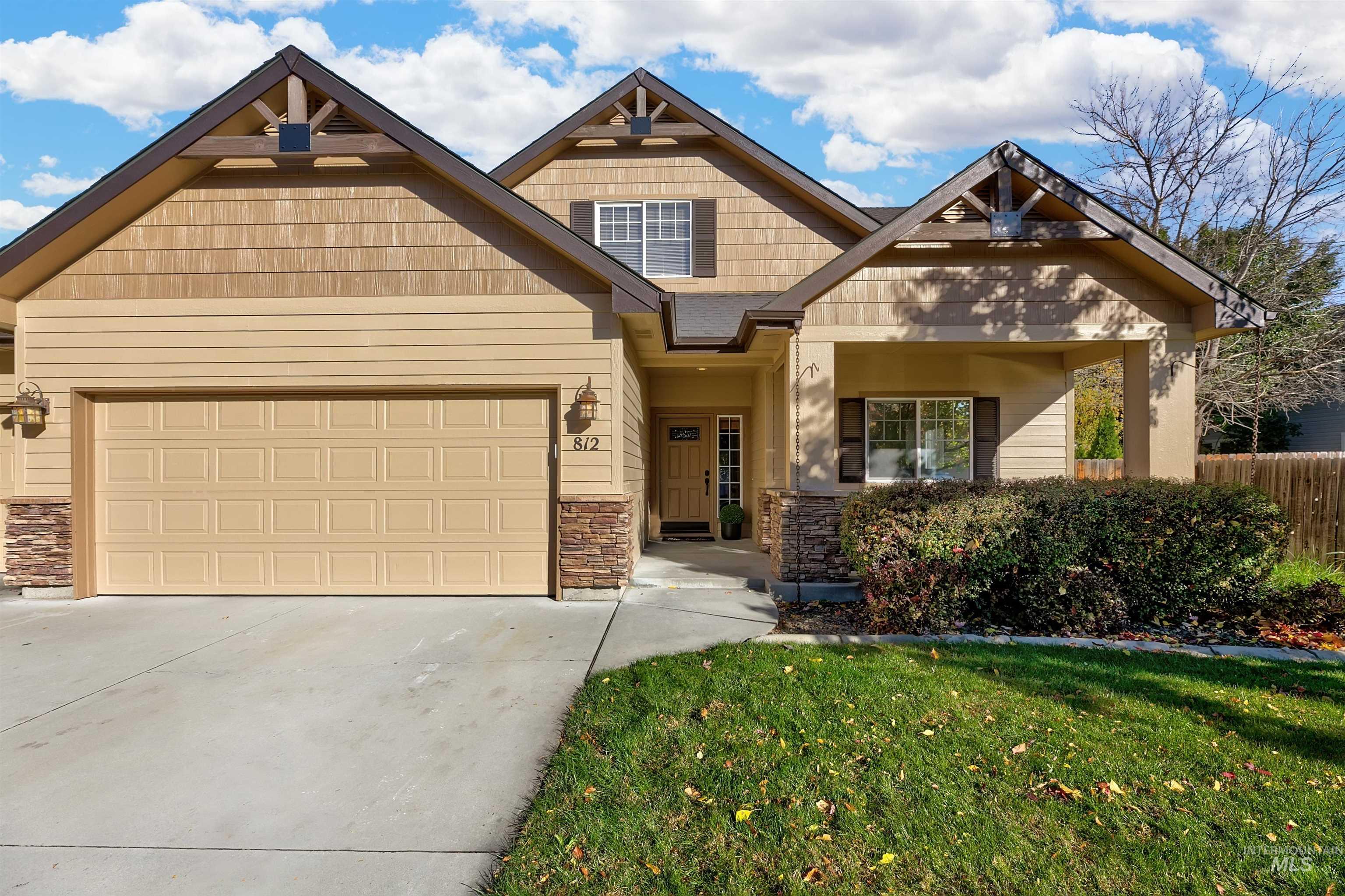 Craftsman-style house featuring stone siding, covered porch, driveway, and an attached garage