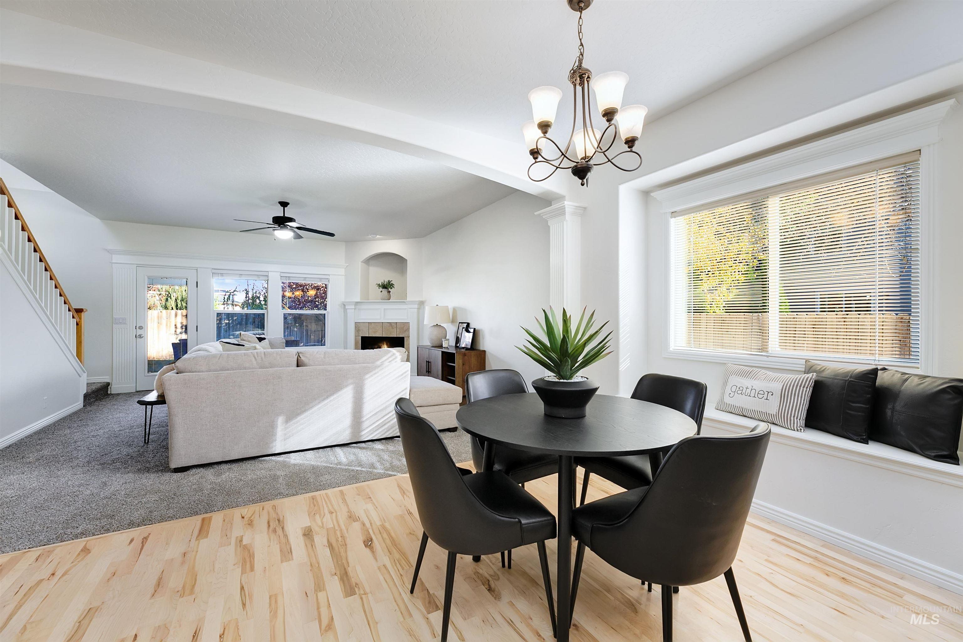 Dining space with light wood finished floors, a tile fireplace, ceiling fan, stairs, and a chandelier