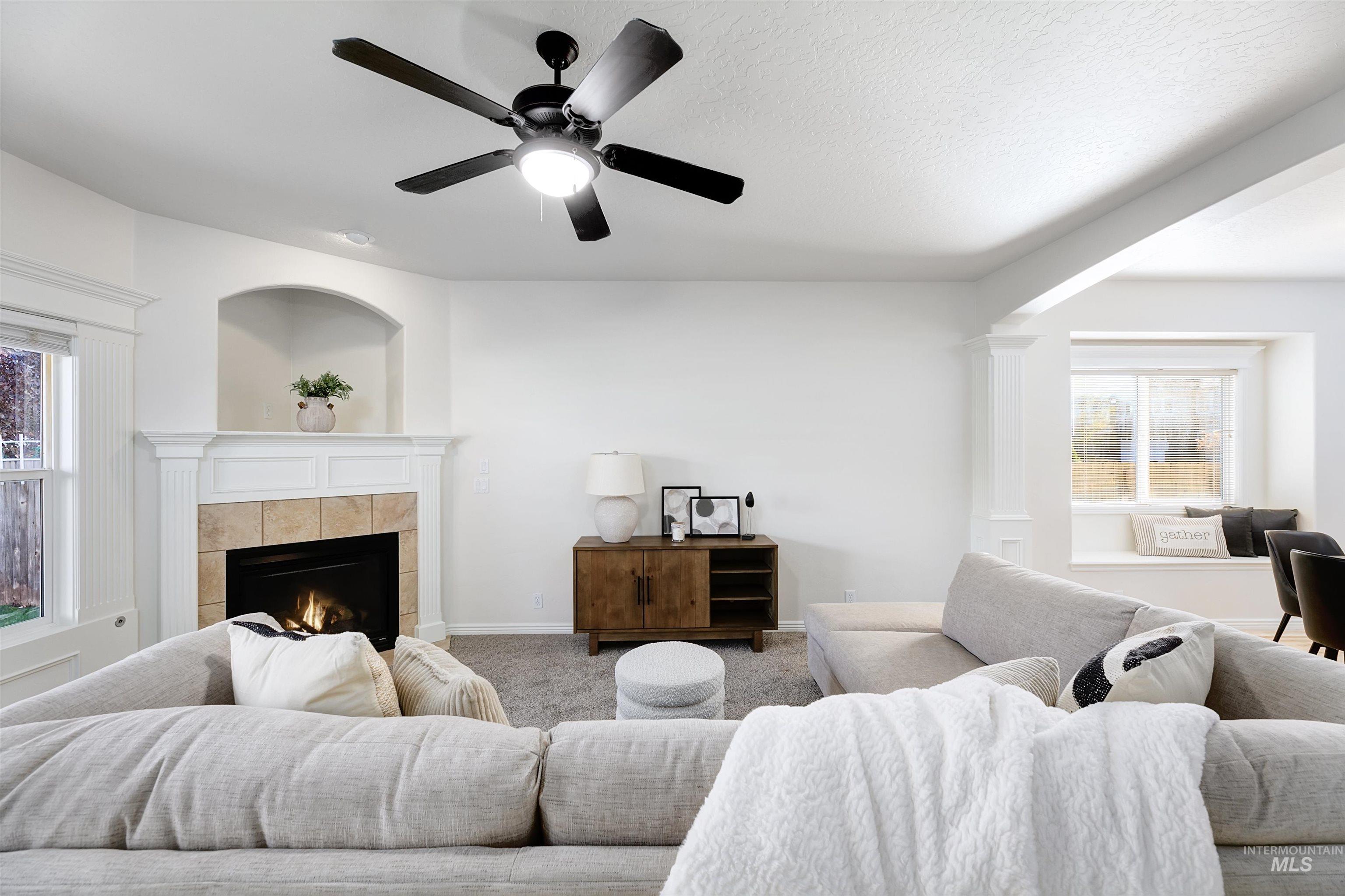 Living area featuring healthy amount of natural light, a ceiling fan, carpet floors, a fireplace, and a textured ceiling