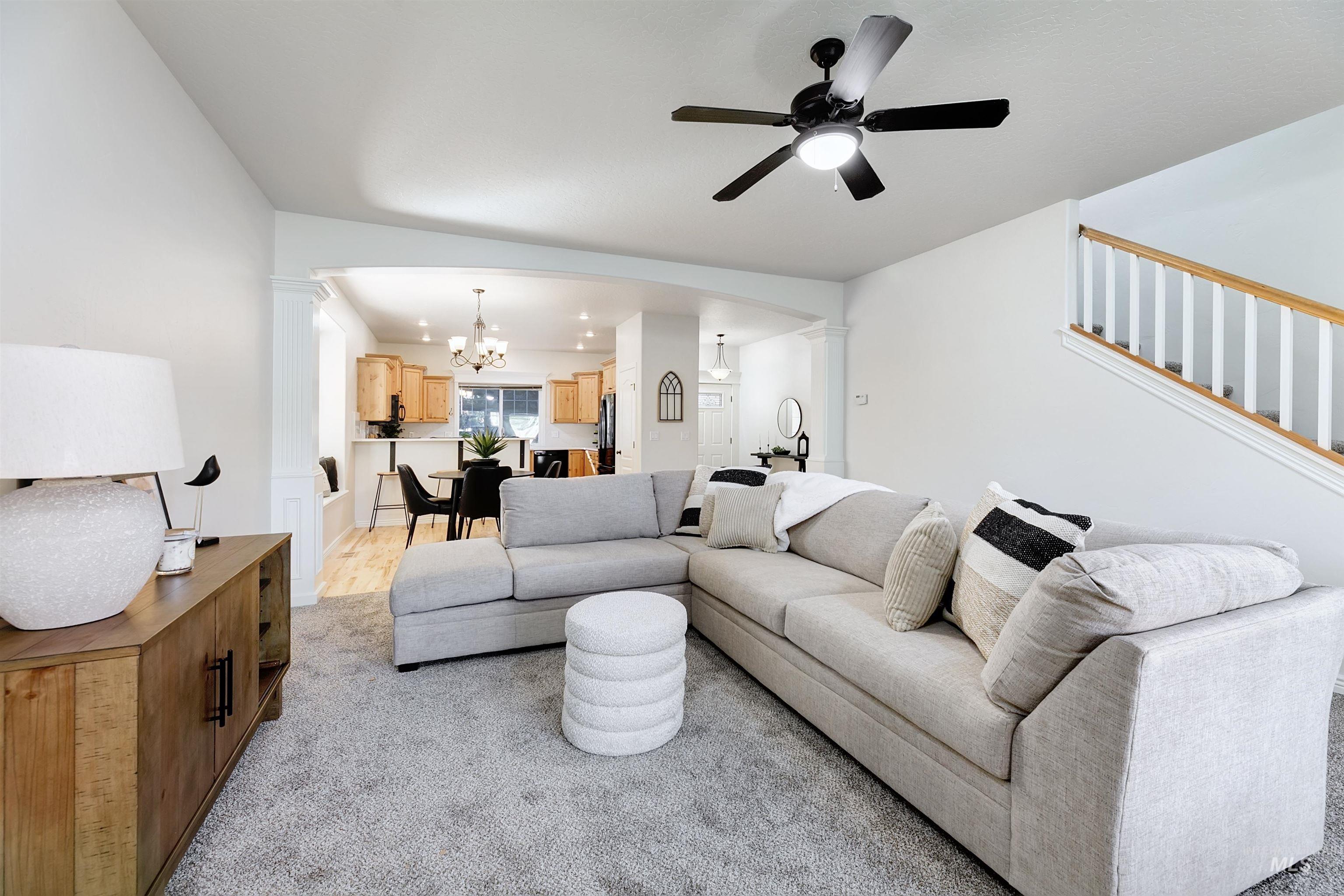 Living area featuring arched walkways, a chandelier, decorative columns, and a ceiling fan