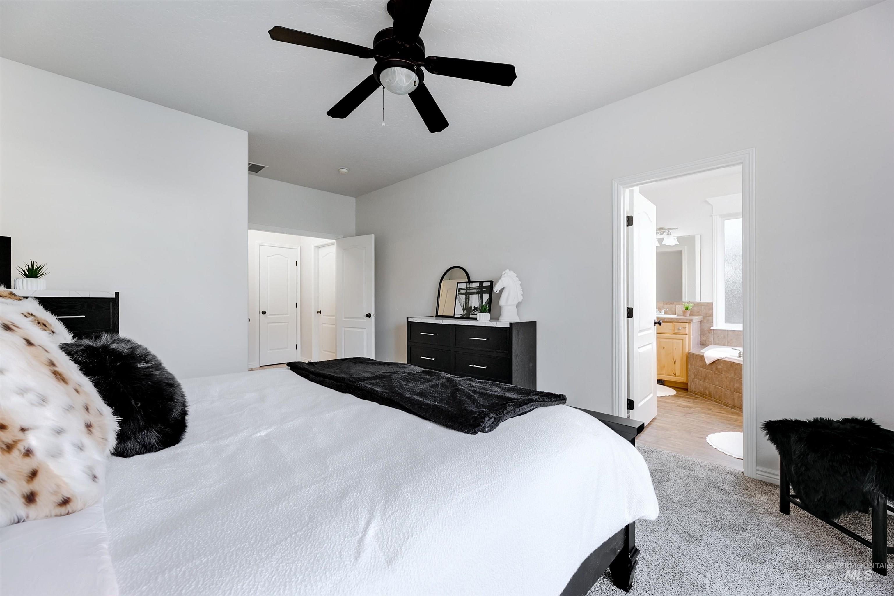 Bedroom with light carpet, ceiling fan, and connected bathroom