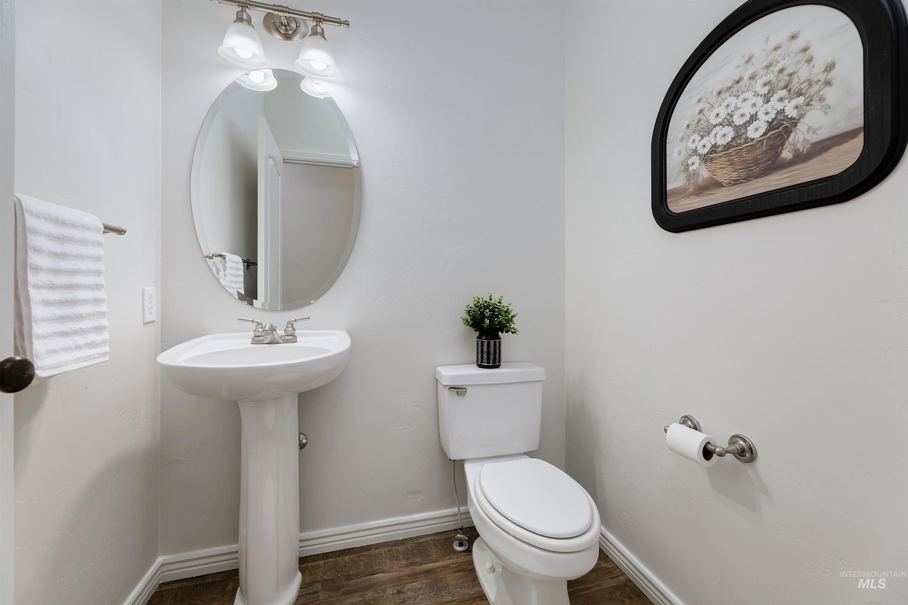Half bath featuring baseboards and dark wood-type flooring