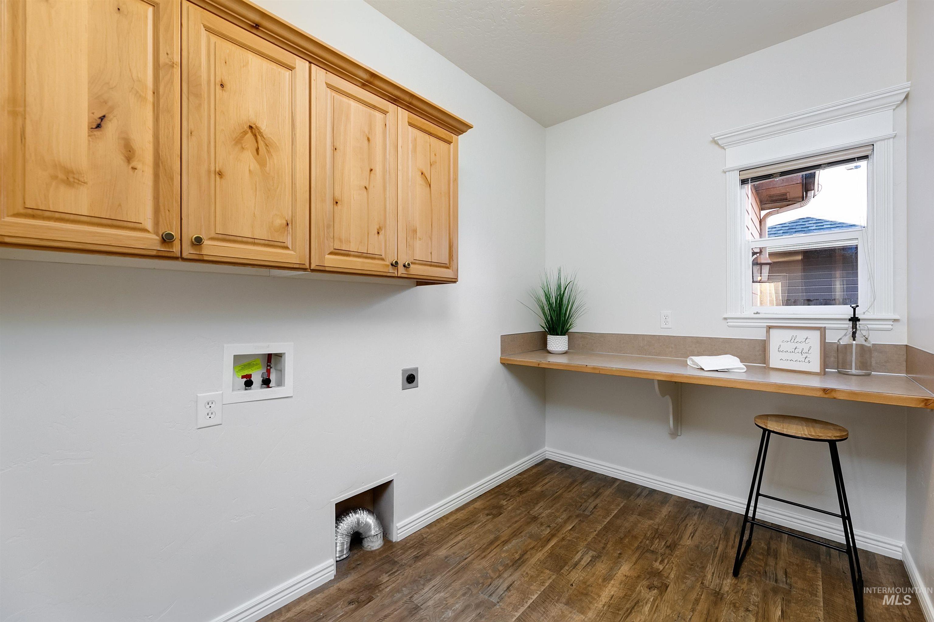 Laundry room featuring dark wood finished floors, washer hookup, hookup for an electric dryer, and cabinet space