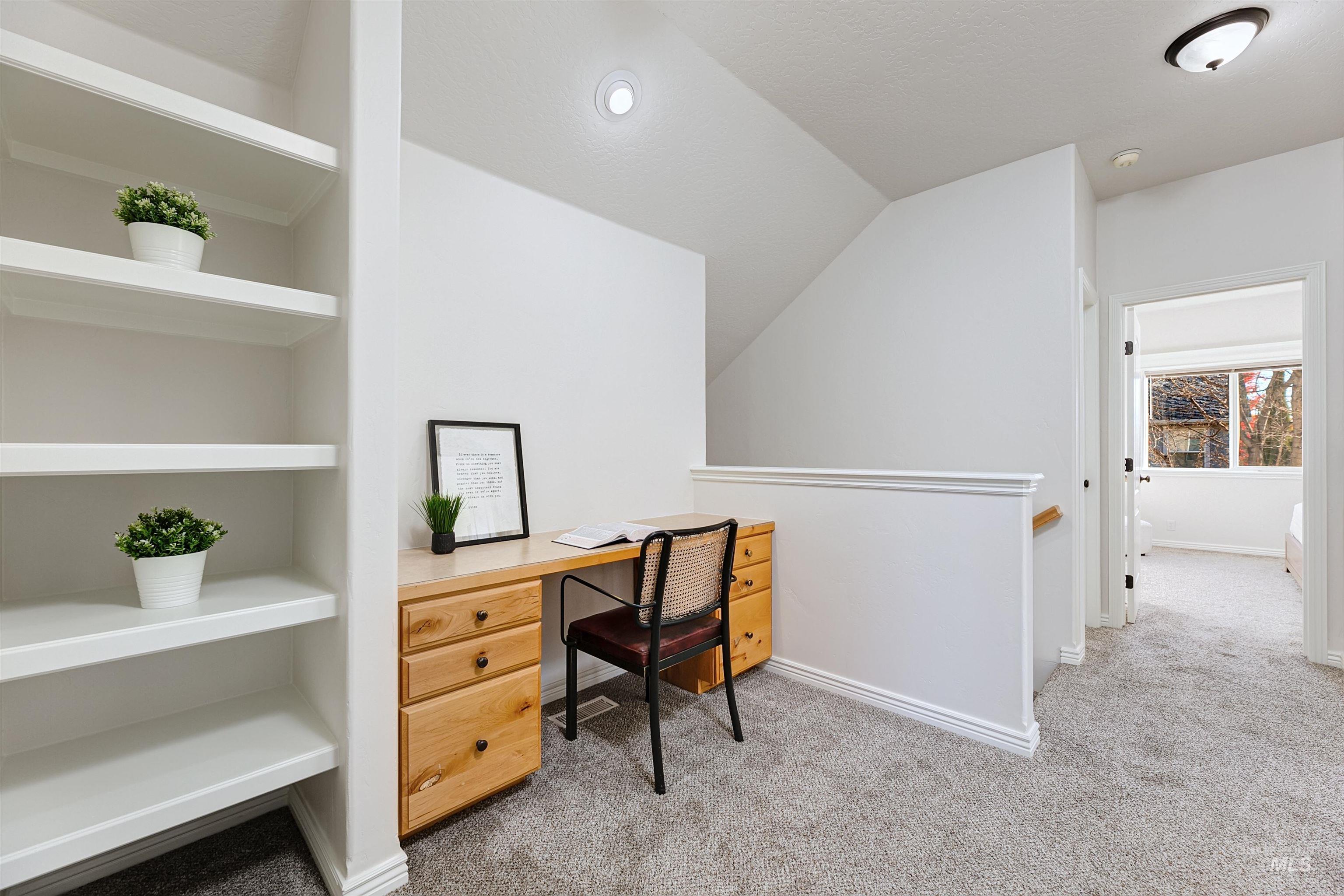 Office space with light carpet and built in shelves