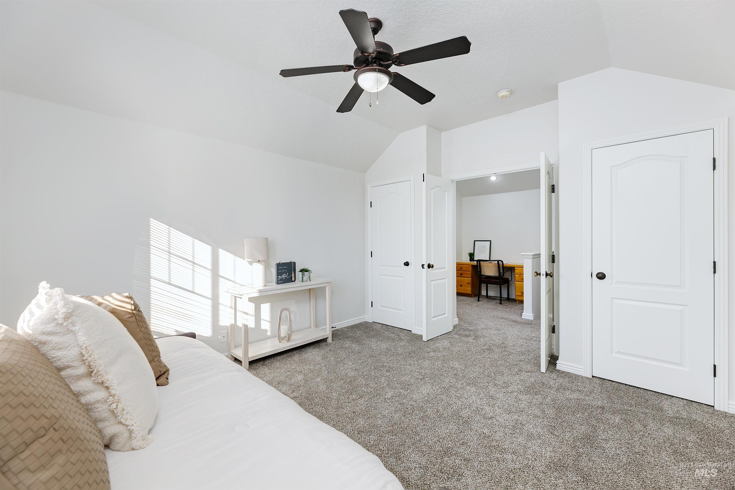 Bedroom with vaulted ceiling, light carpet, and ceiling fan