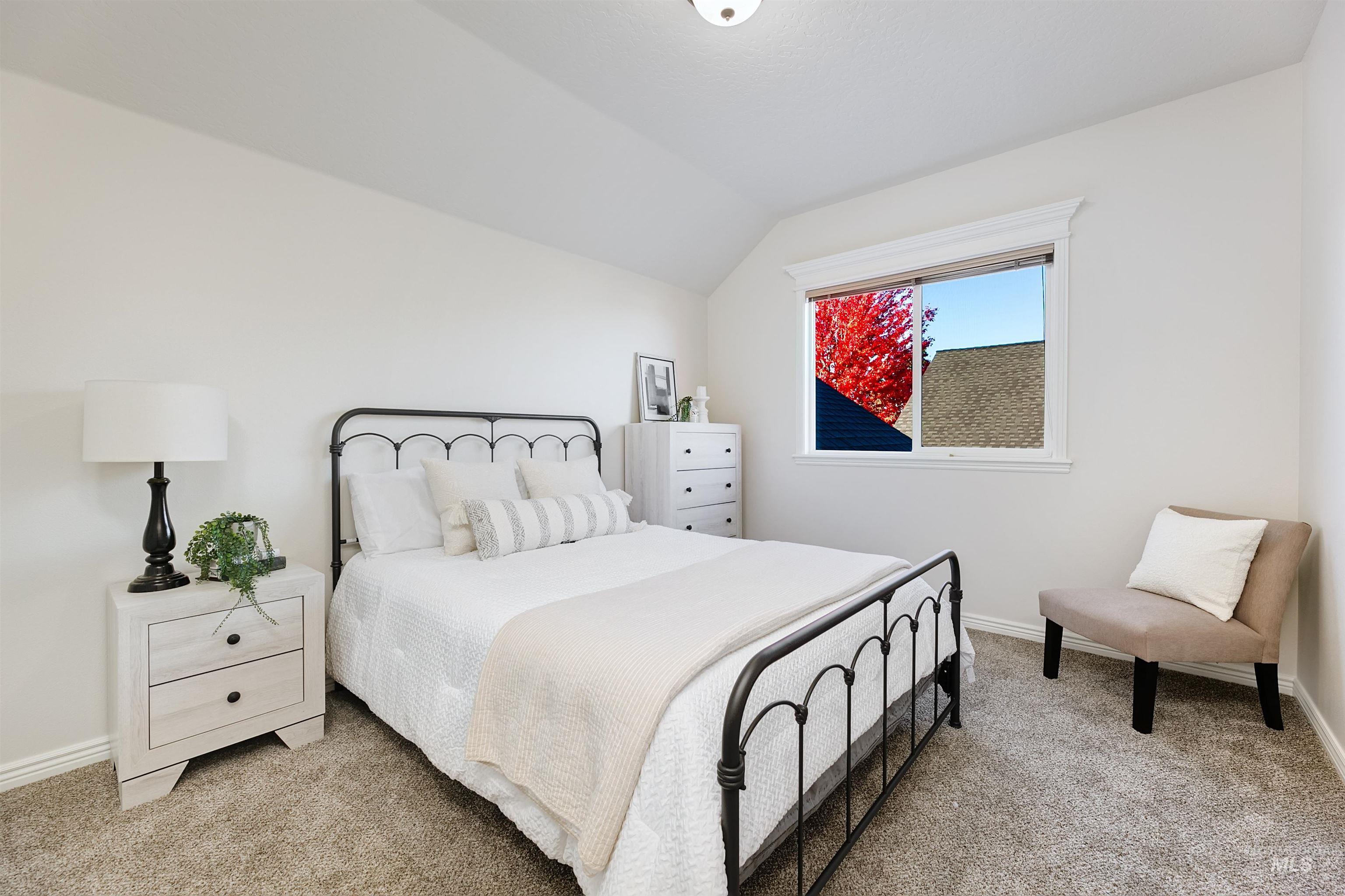Bedroom with light colored carpet and lofted ceiling