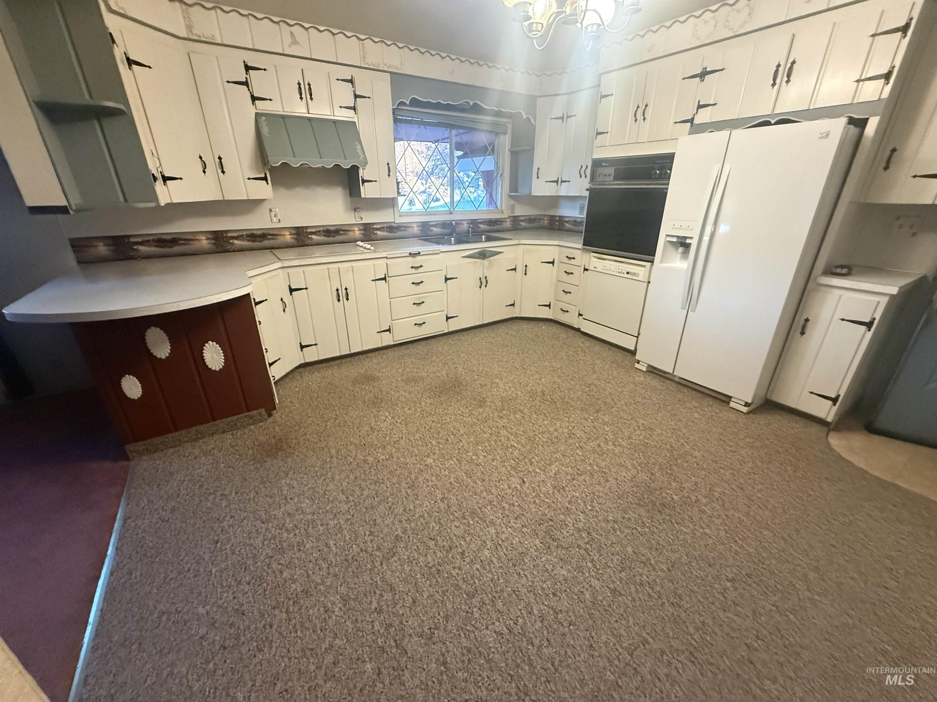 Kitchen with white cabinets, white appliances, light countertops, and ventilation hood