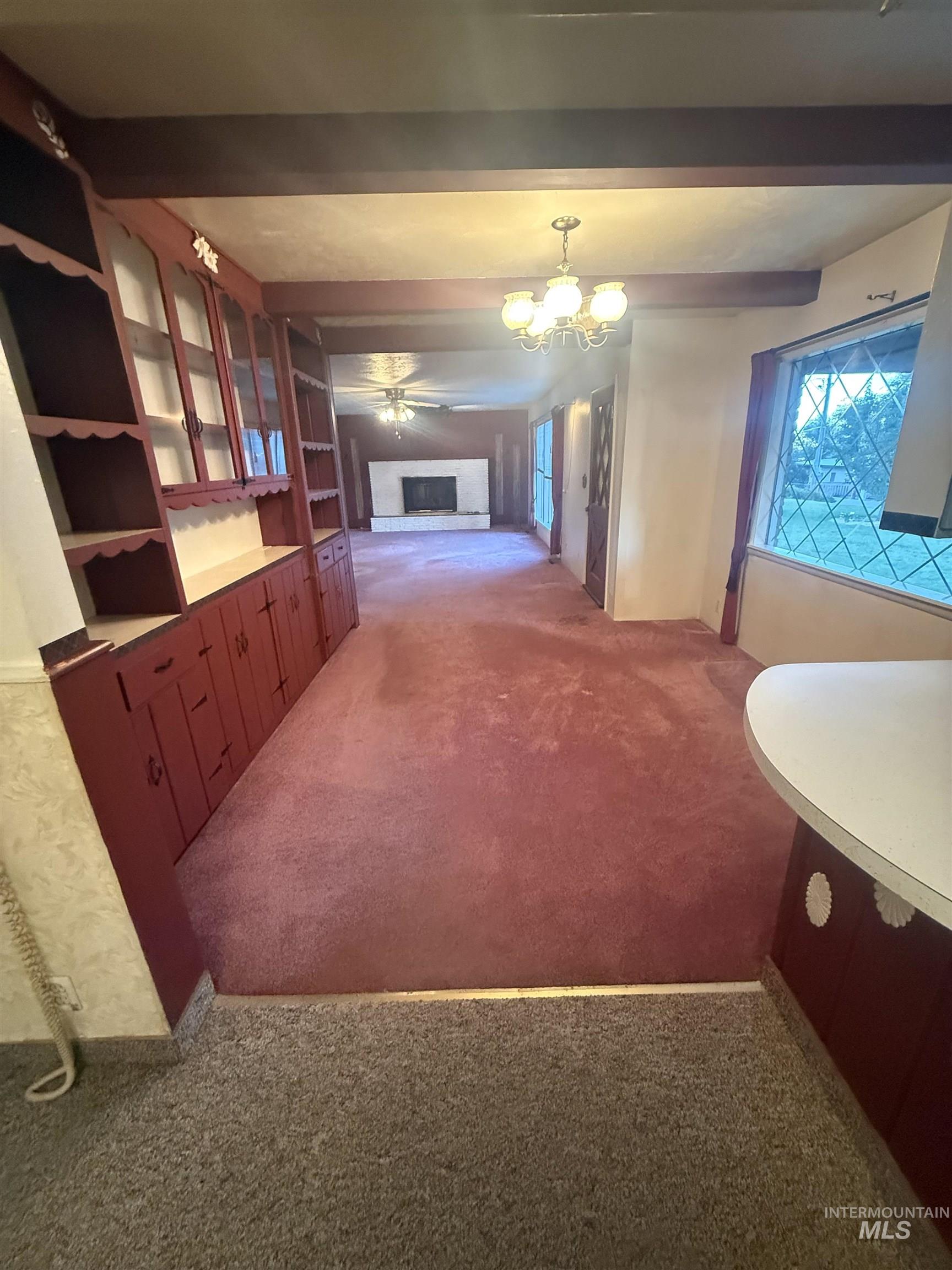 Hallway featuring beam ceiling, light colored carpet, and a chandelier