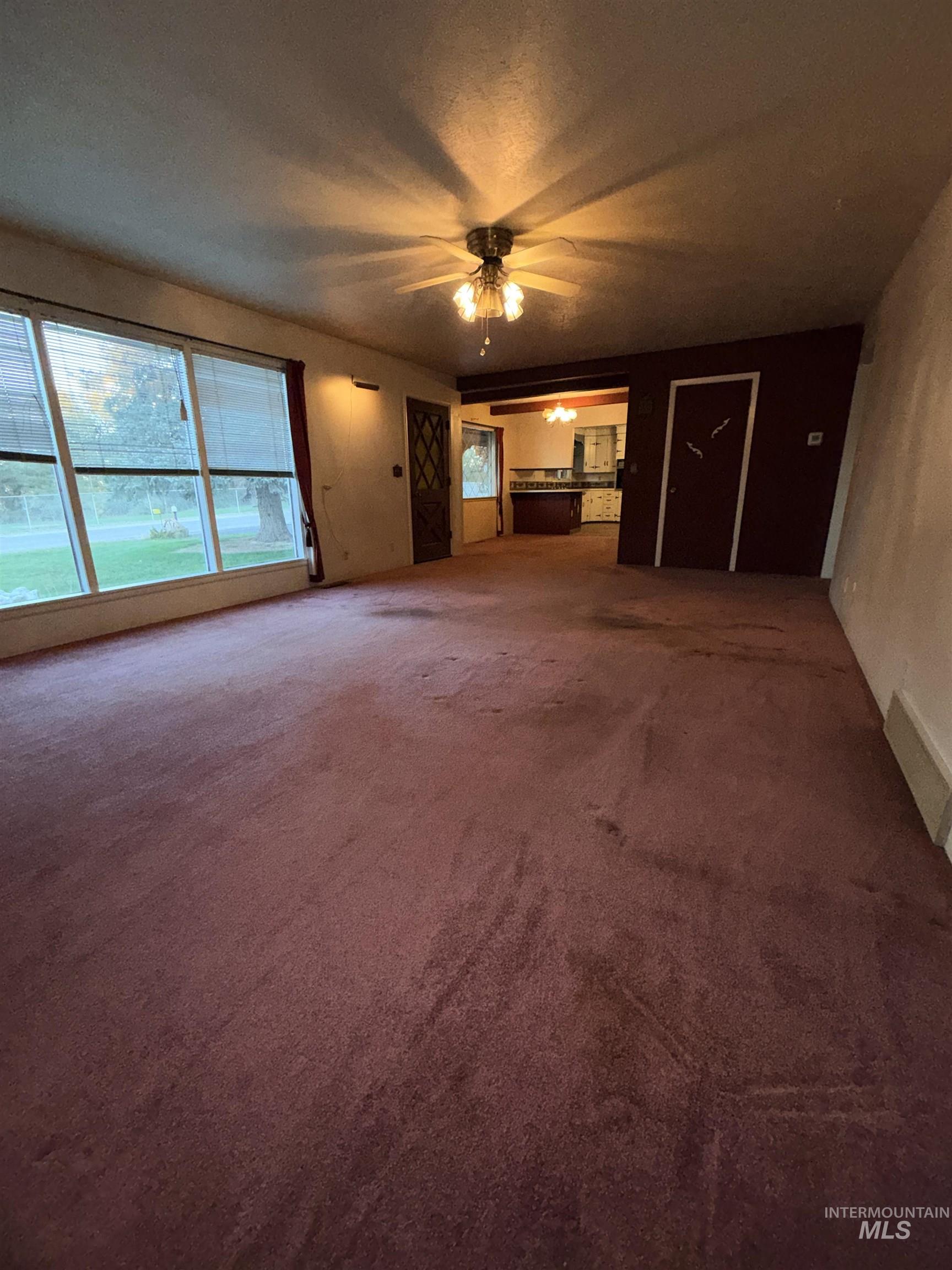 Unfurnished living room with dark carpet, ceiling fan, plenty of natural light, and a textured ceiling