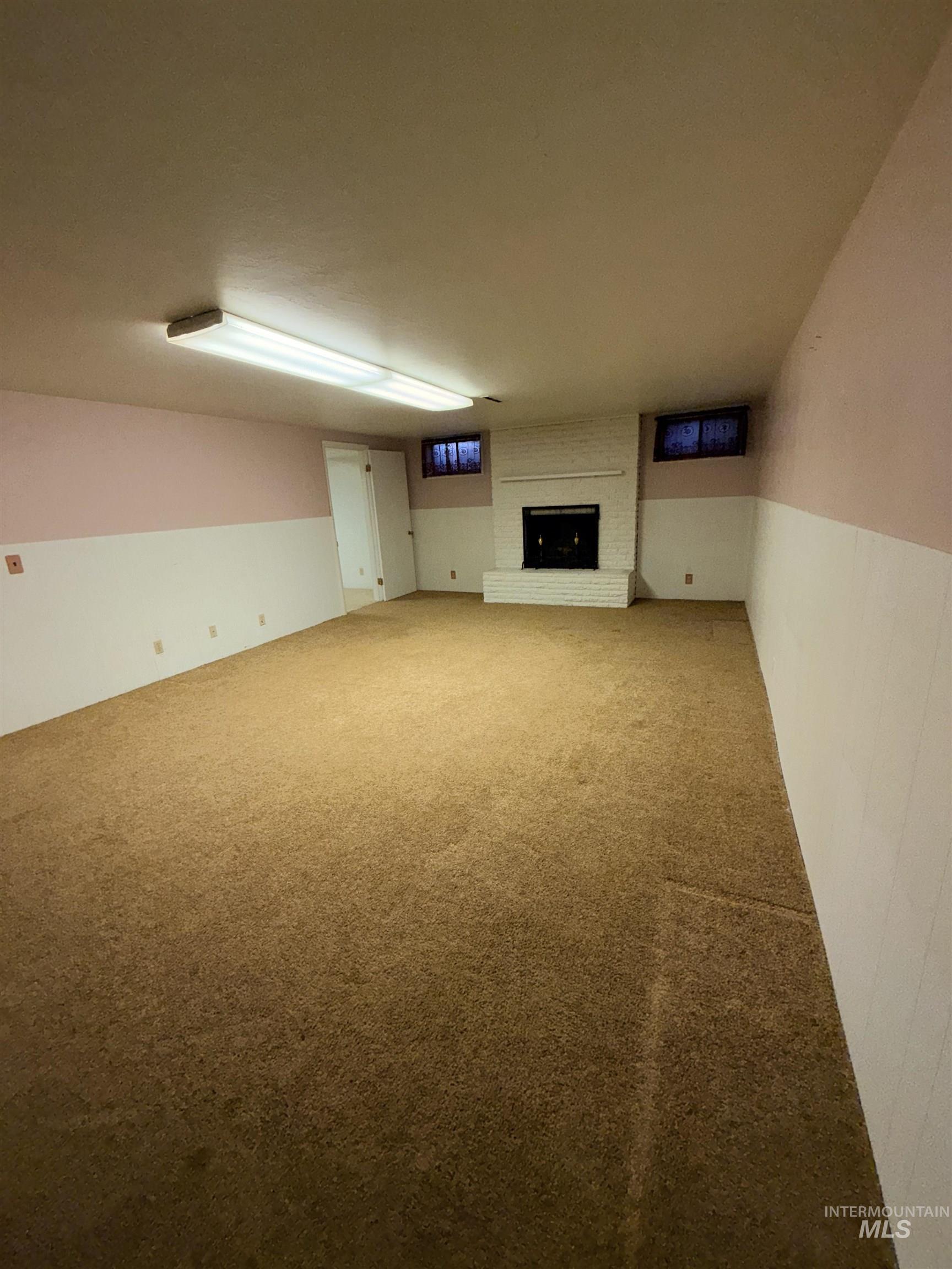 Unfurnished living room with carpet and a brick fireplace