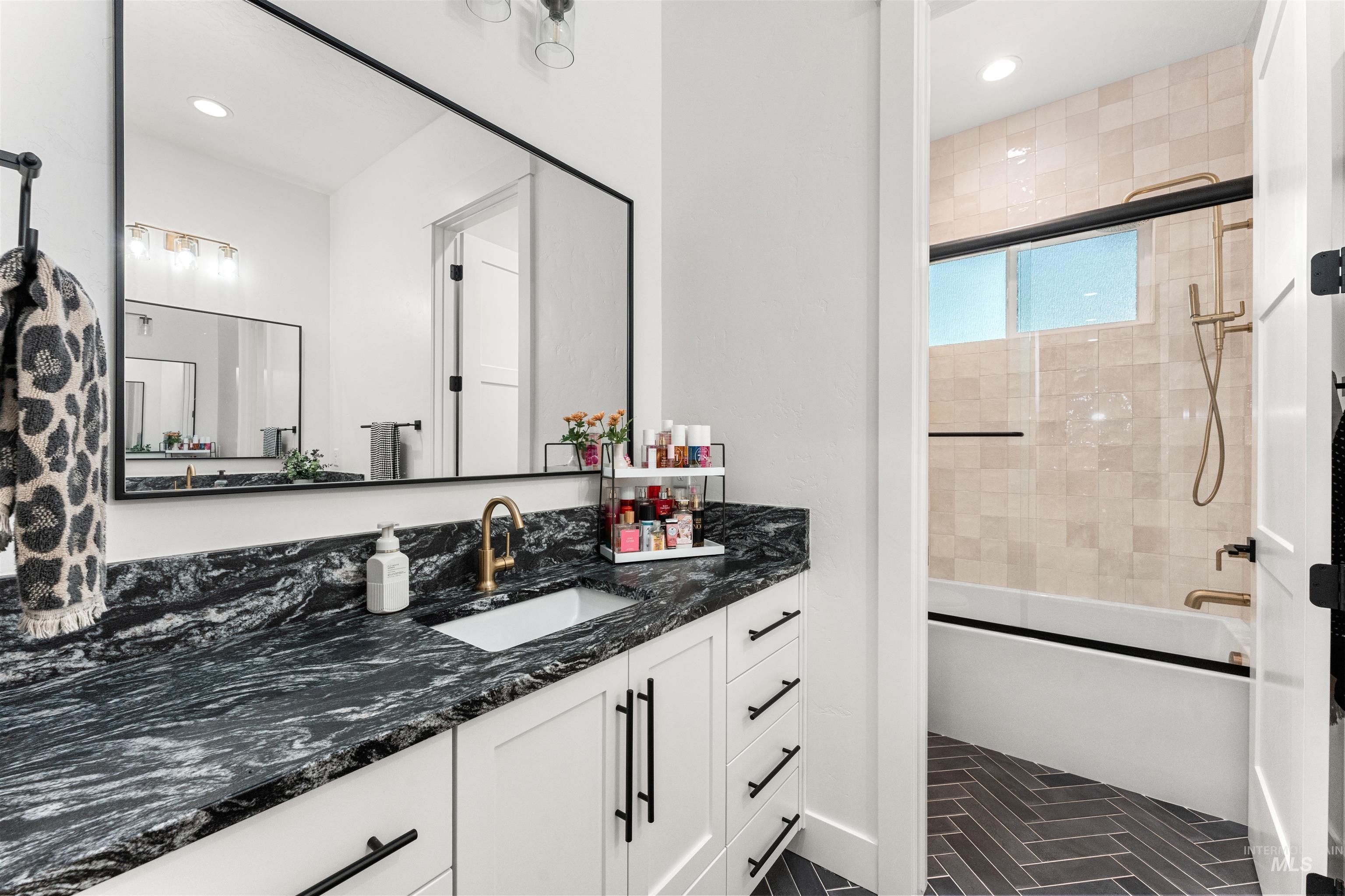 Full bathroom featuring vanity, shower / bath combination with glass door, dark tile patterned flooring, and recessed lighting