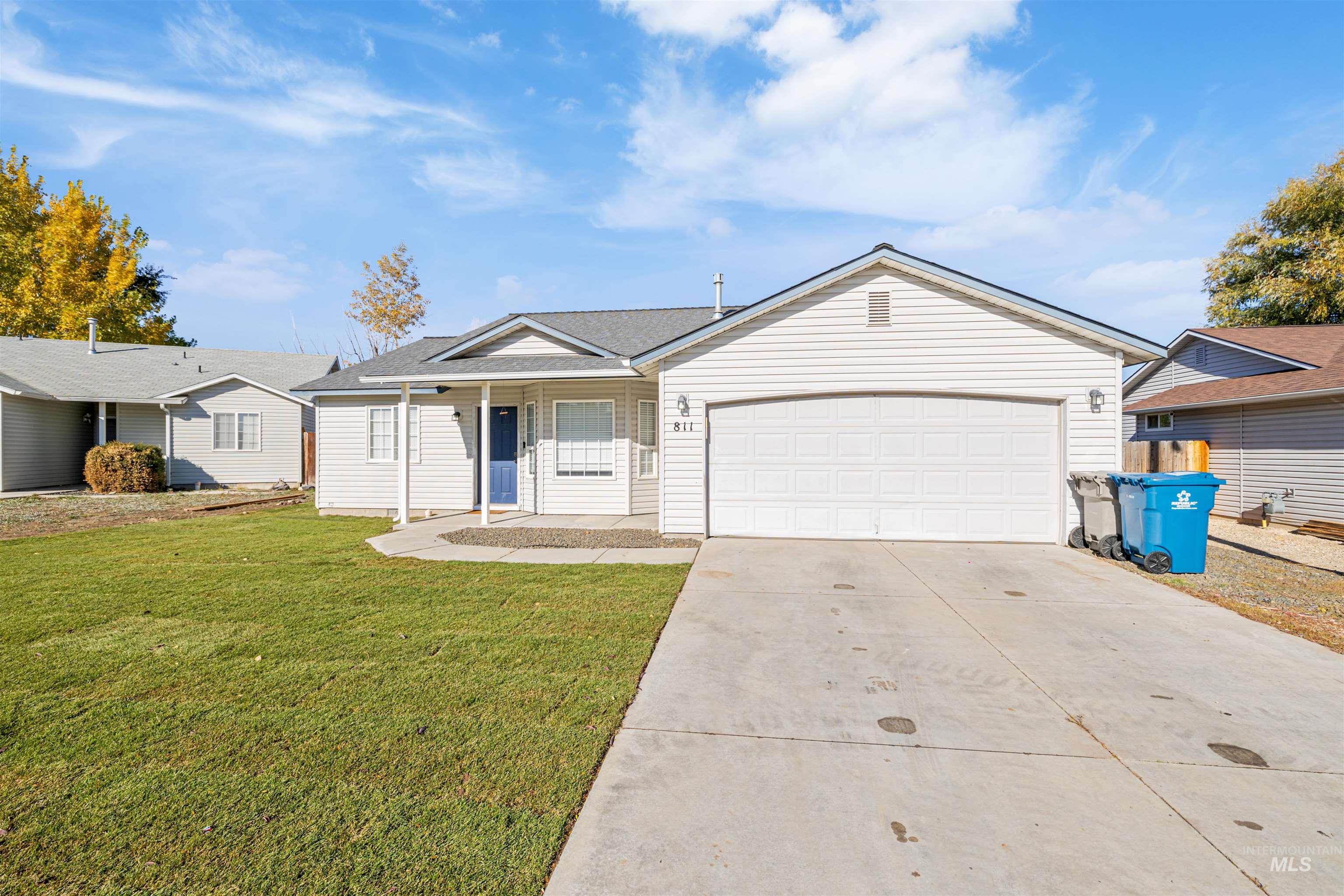 Ranch-style home with a front yard, driveway, covered porch, and a garage