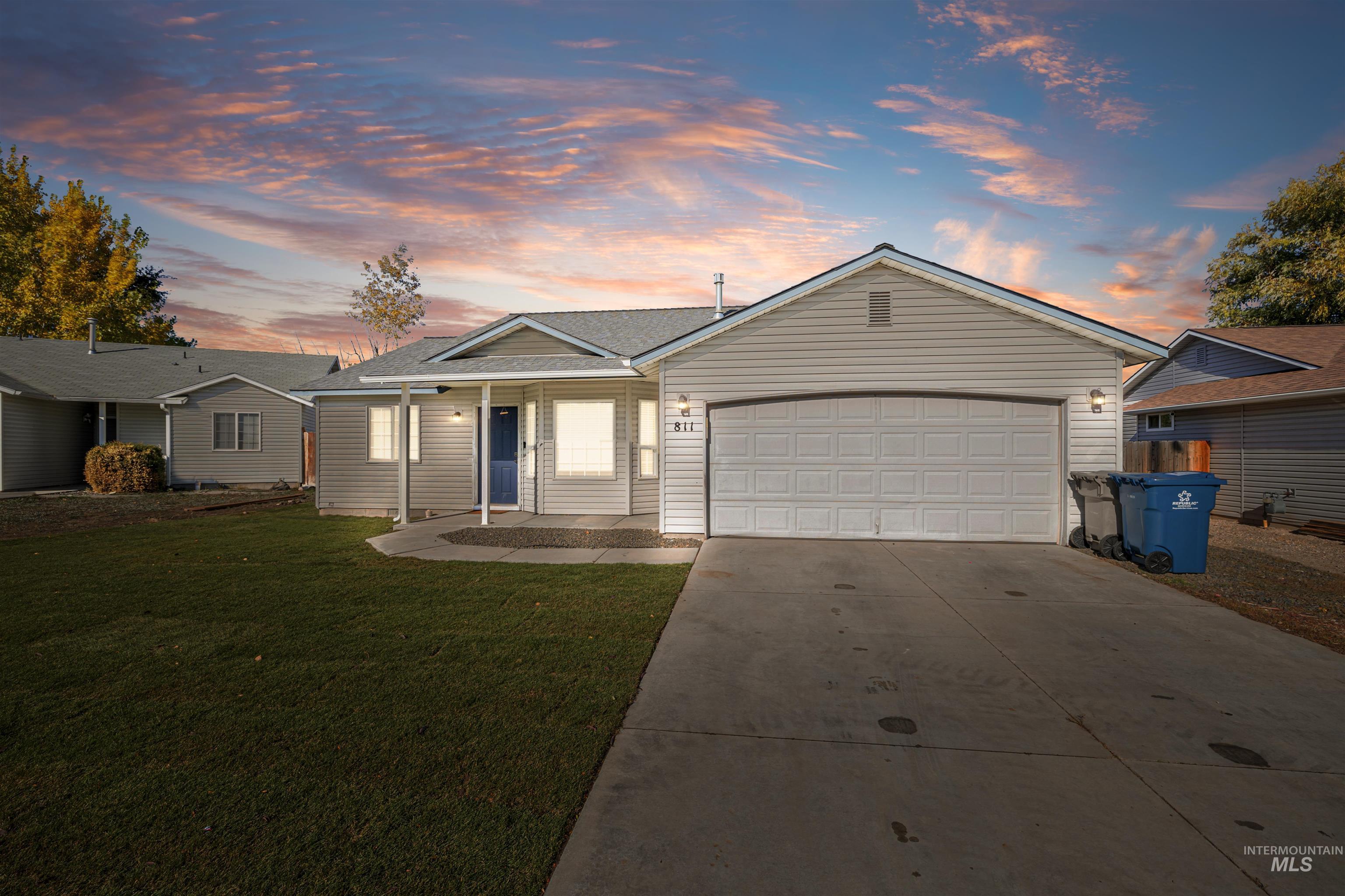 Single story home with driveway, a front lawn, an attached garage, covered porch, and roof with shingles
