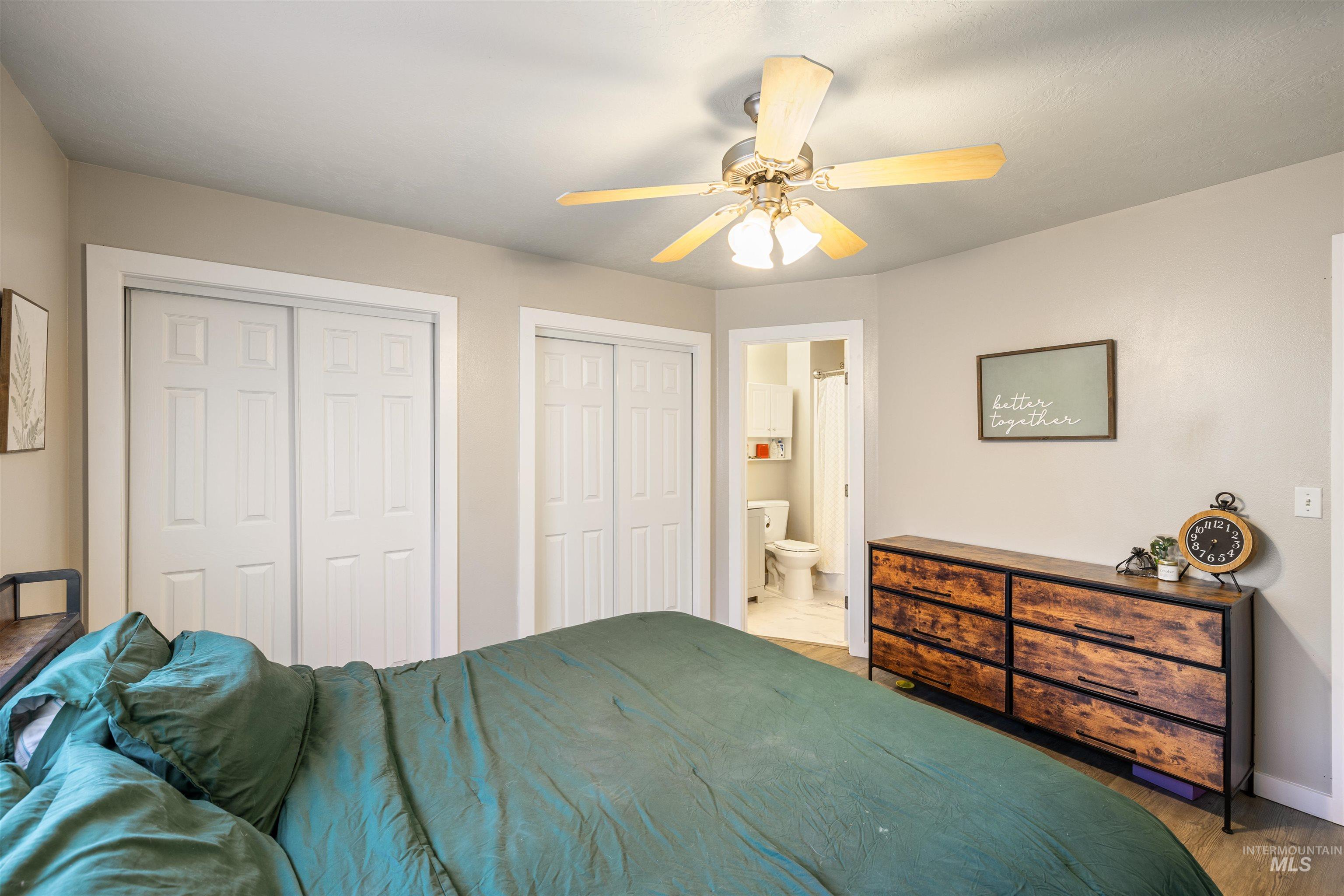 Bedroom with multiple closets, a ceiling fan, light wood finished floors, and connected bathroom