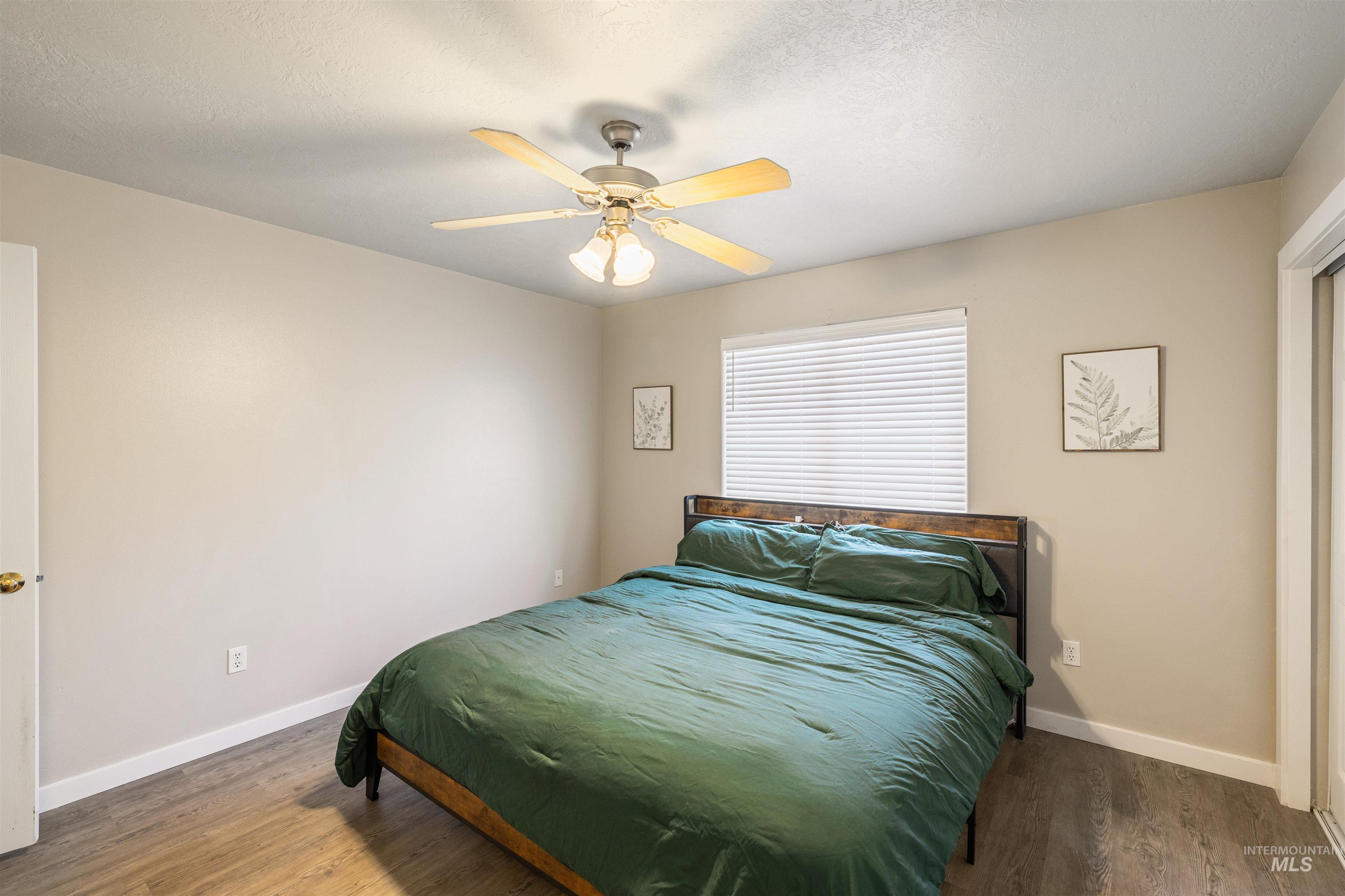 Bedroom with wood finished floors, a textured ceiling, and a ceiling fan