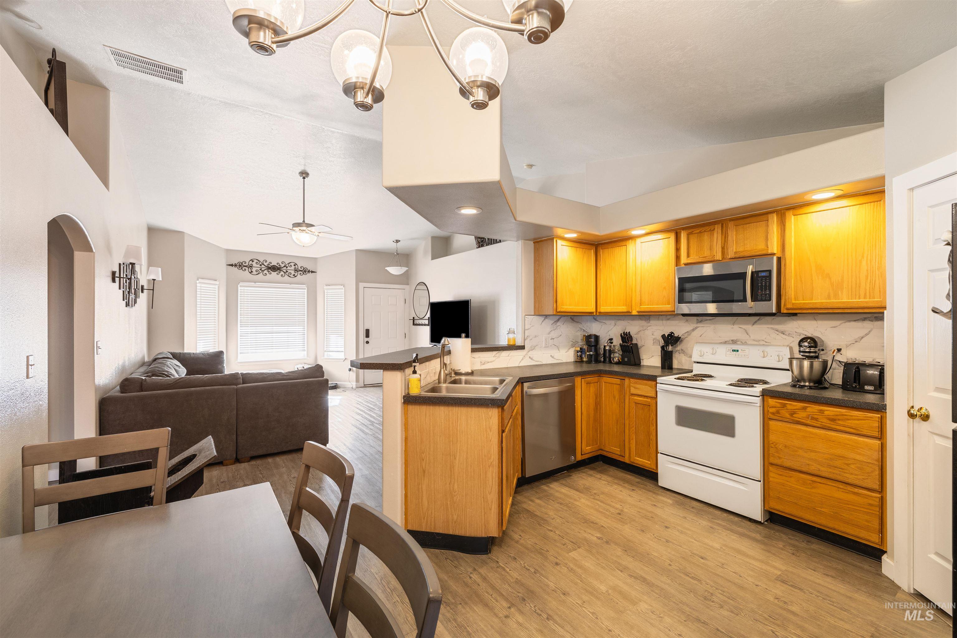 Kitchen featuring dark countertops, stainless steel appliances, open floor plan, a peninsula, and lofted ceiling