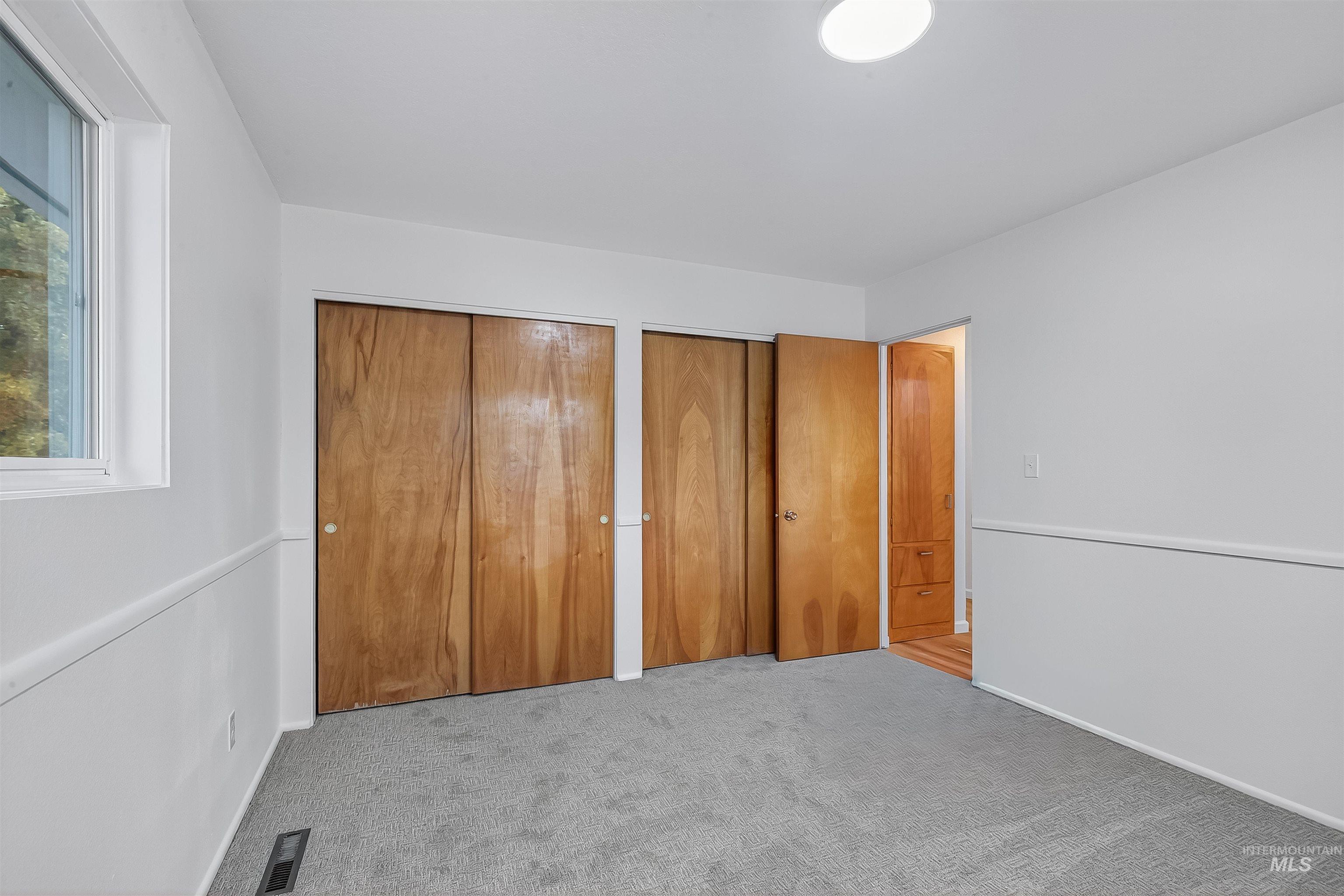 Unfurnished bedroom featuring multiple closets and light carpet