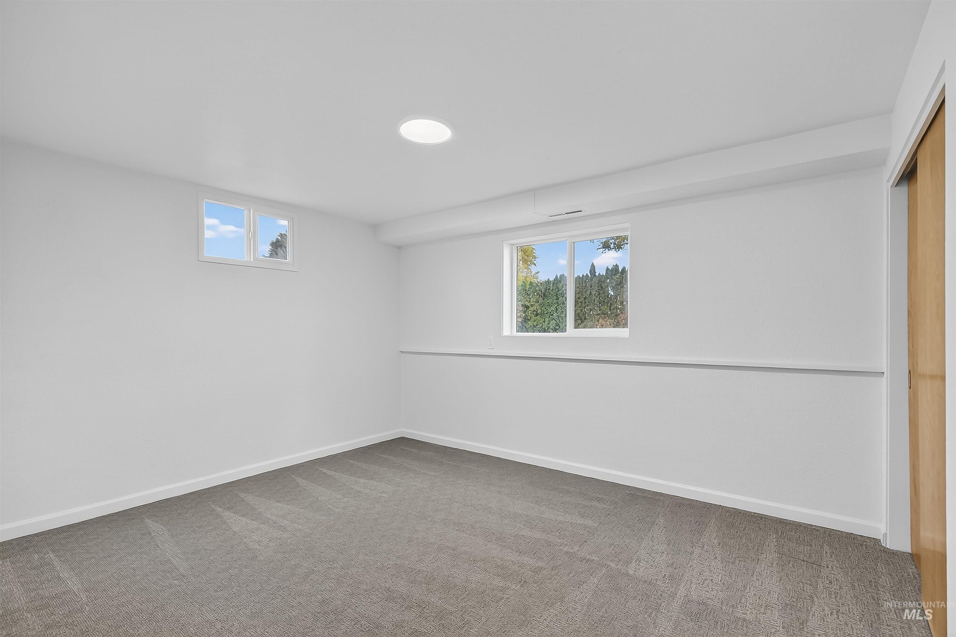 Unfurnished bedroom with multiple windows, light carpet, and a closet