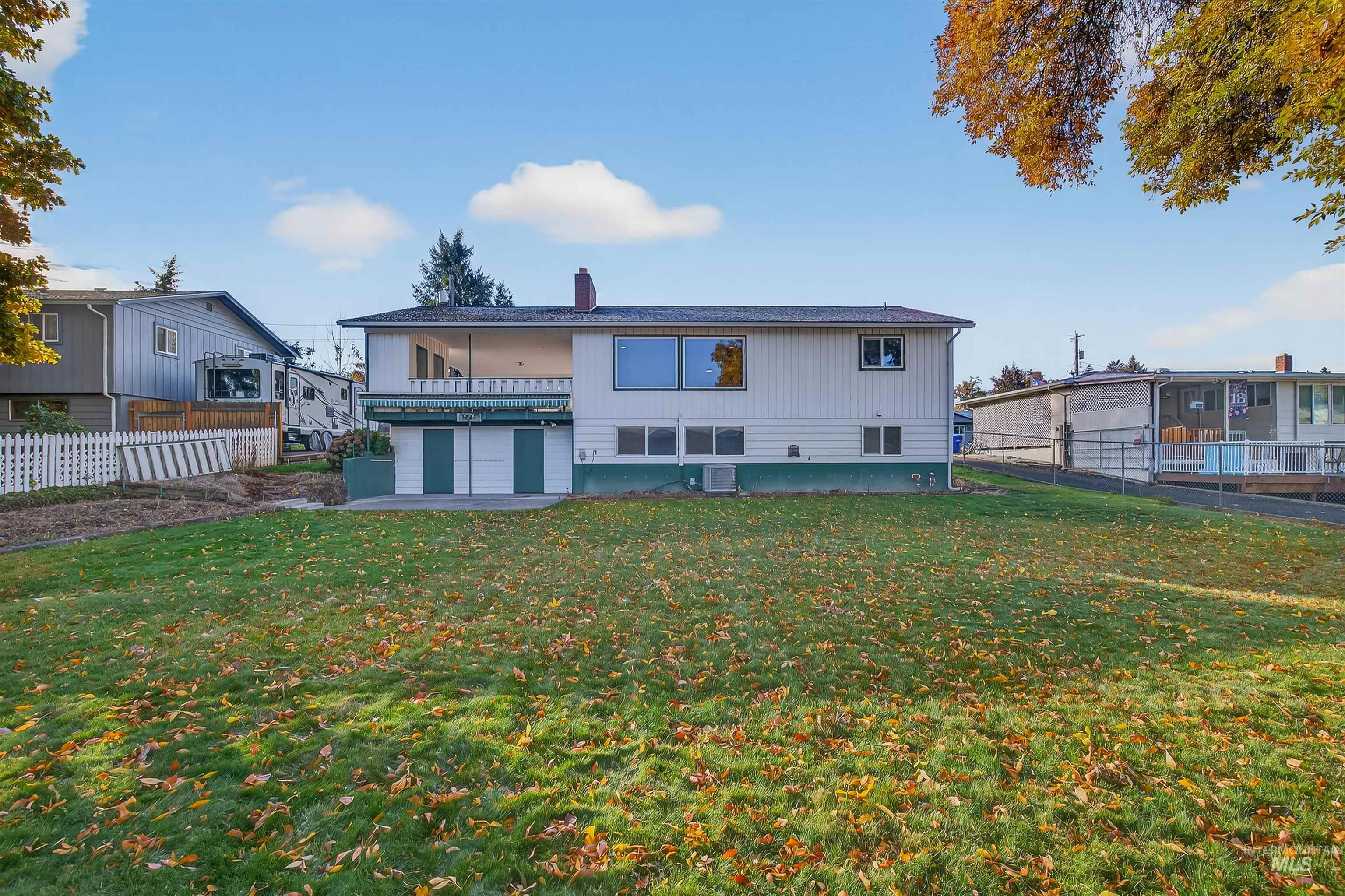 Rear view of house featuring a fenced backyard, a chimney, a patio, and a balcony