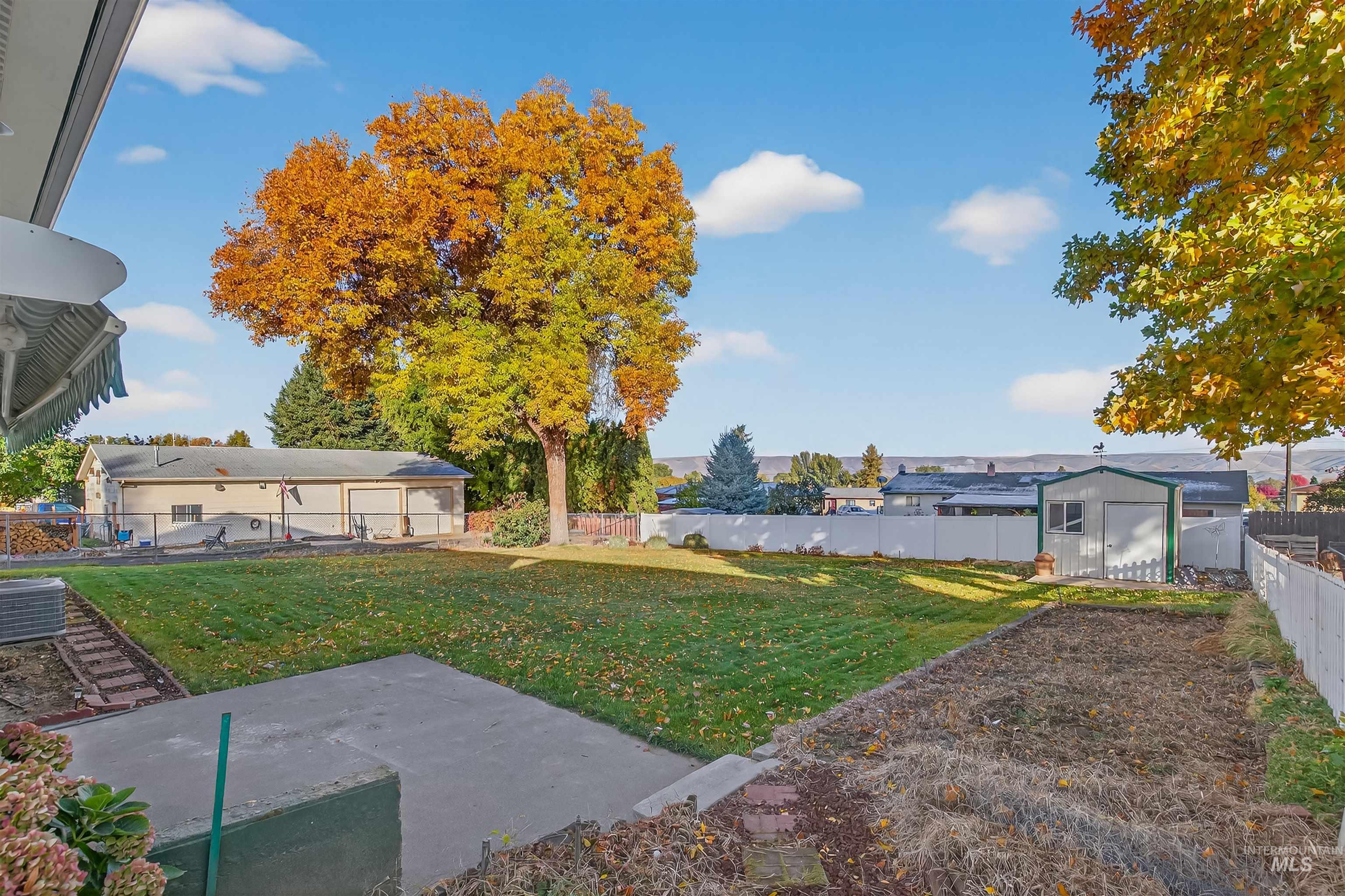 Fenced backyard with a storage unit and a patio