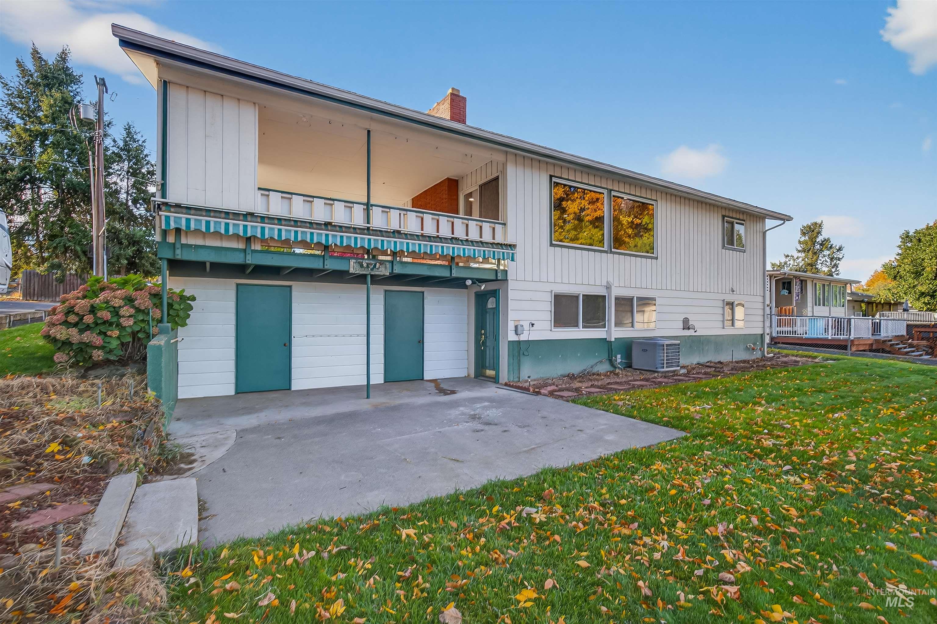Rear view of house with a lawn, a patio, a balcony, and a chimney