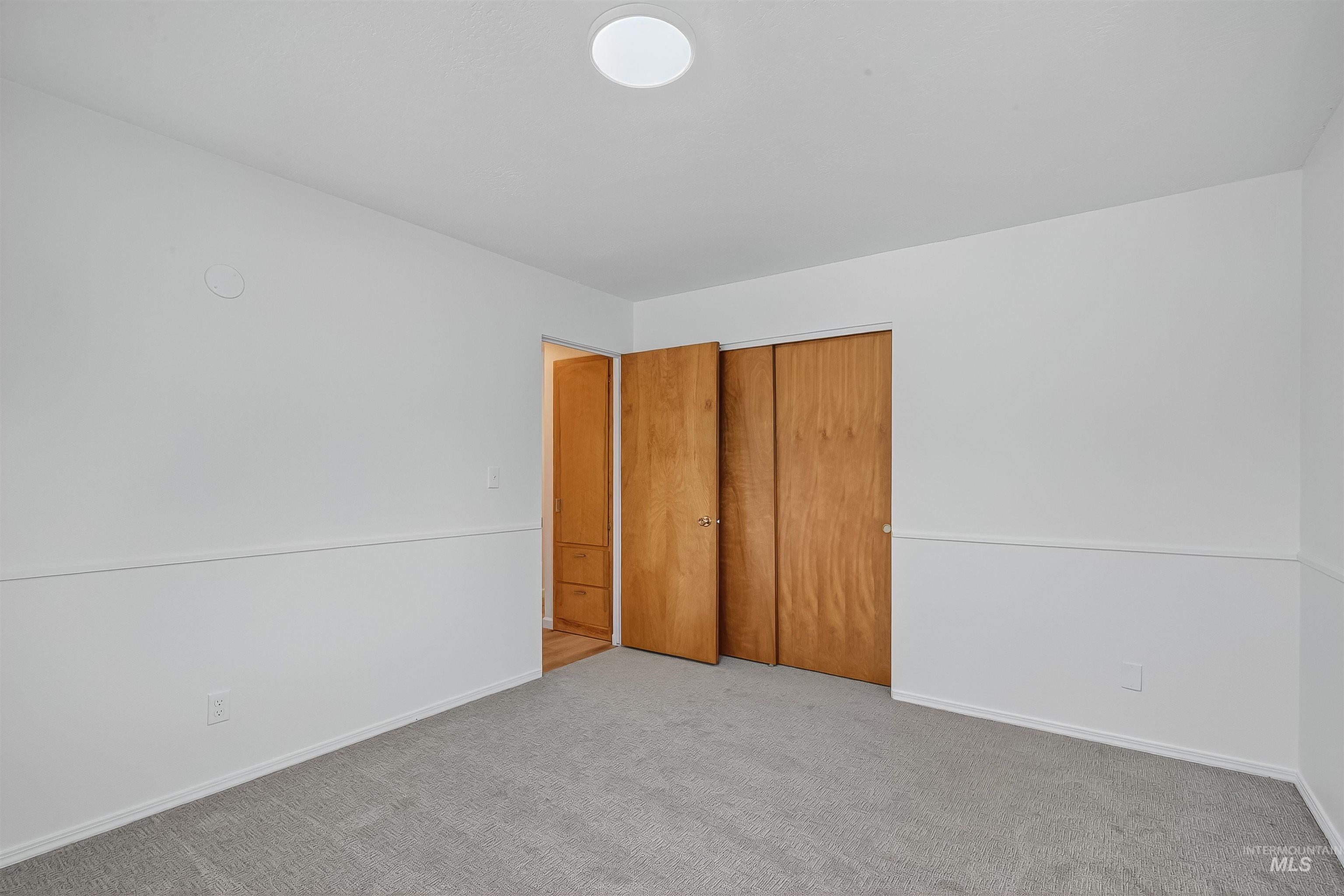 Unfurnished bedroom with light carpet and a closet