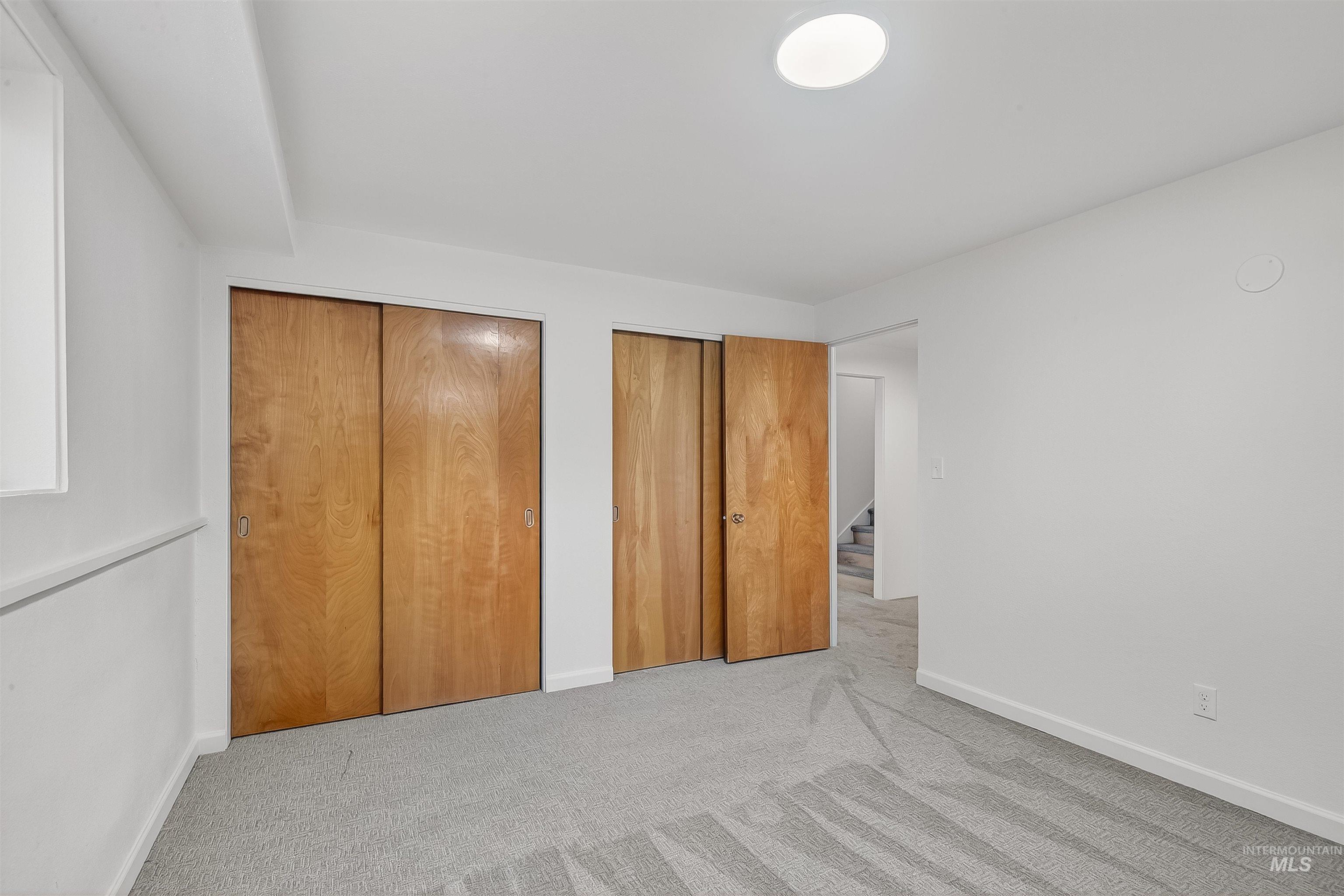 Unfurnished bedroom with two closets and carpet