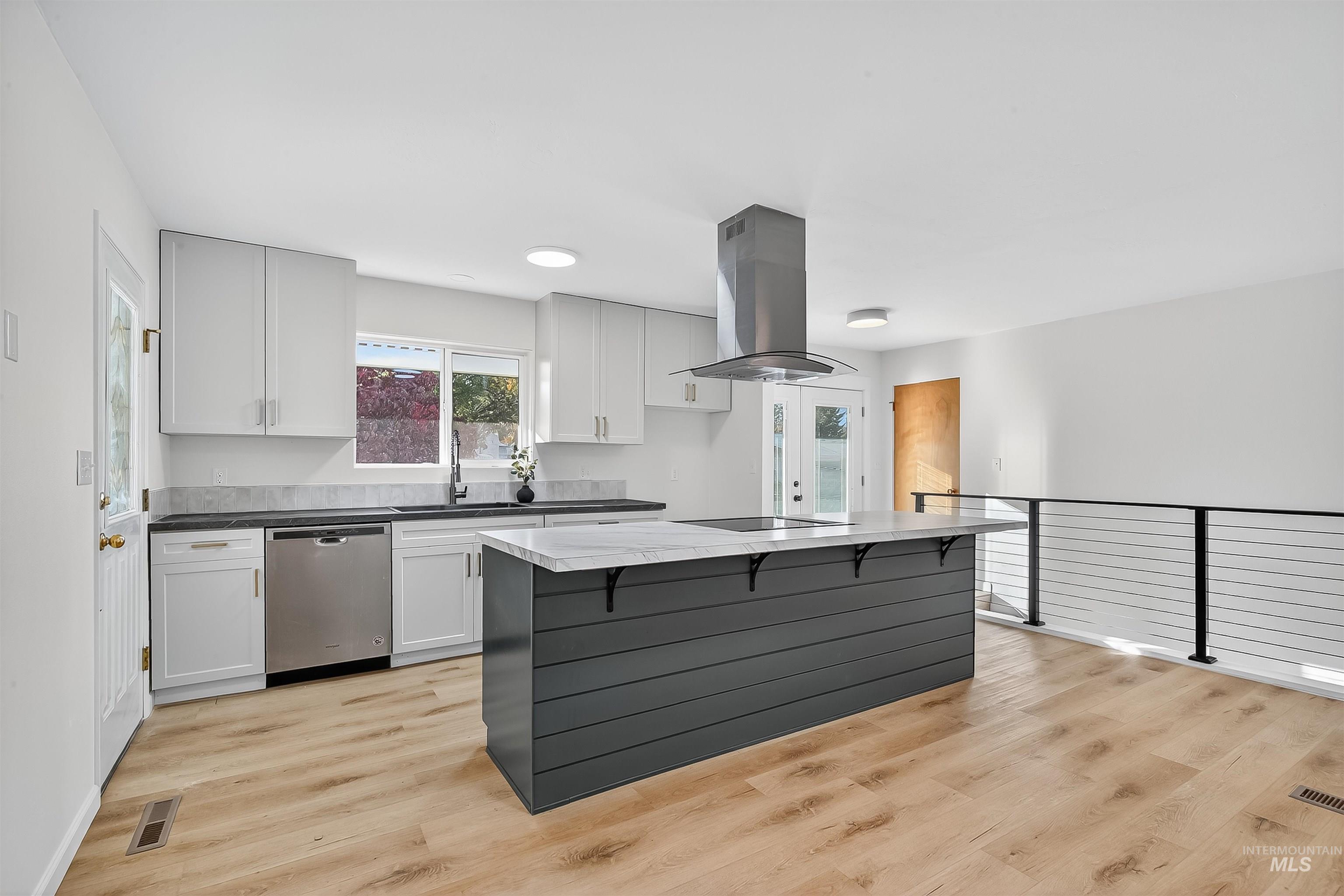 Kitchen featuring white cabinetry, gray cabinetry, stainless steel dishwasher, island range hood, and light wood-type flooring