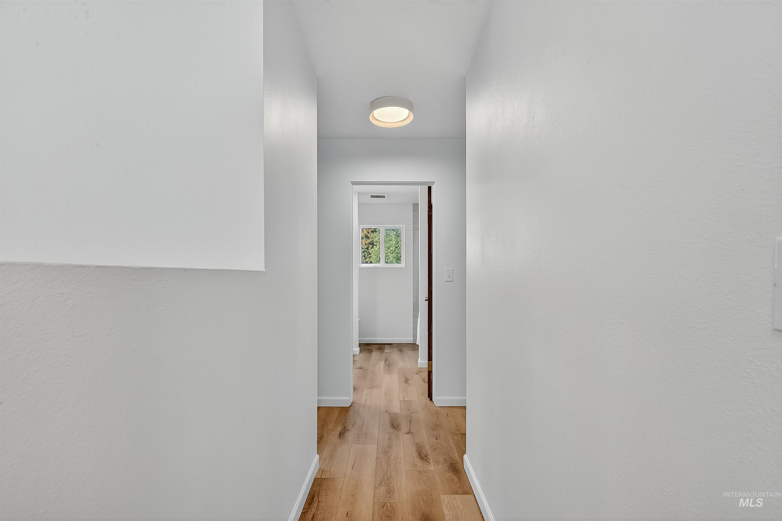 Hallway with light wood-type flooring and baseboards