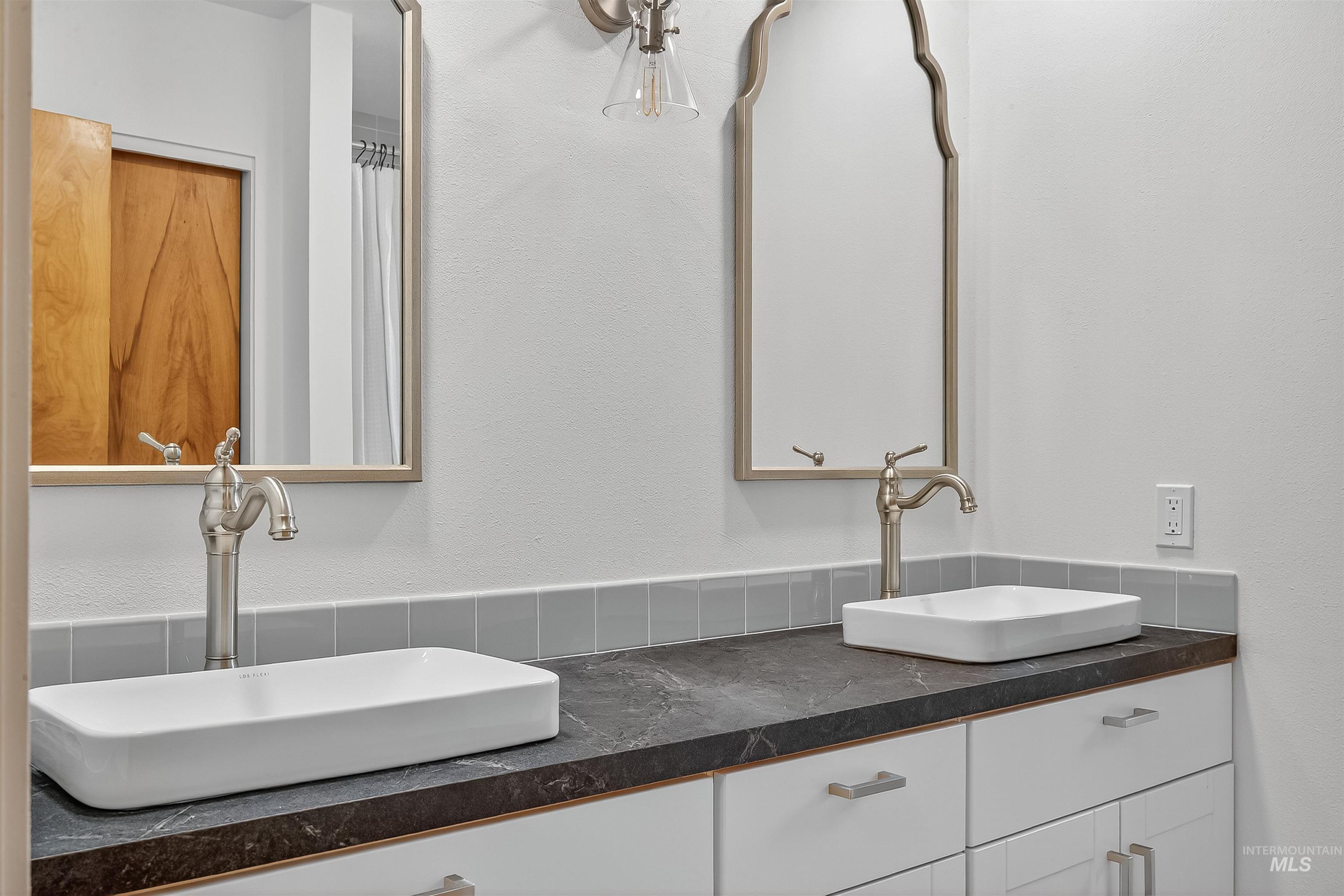 Bathroom with double vanity, curtained shower, and a textured wall