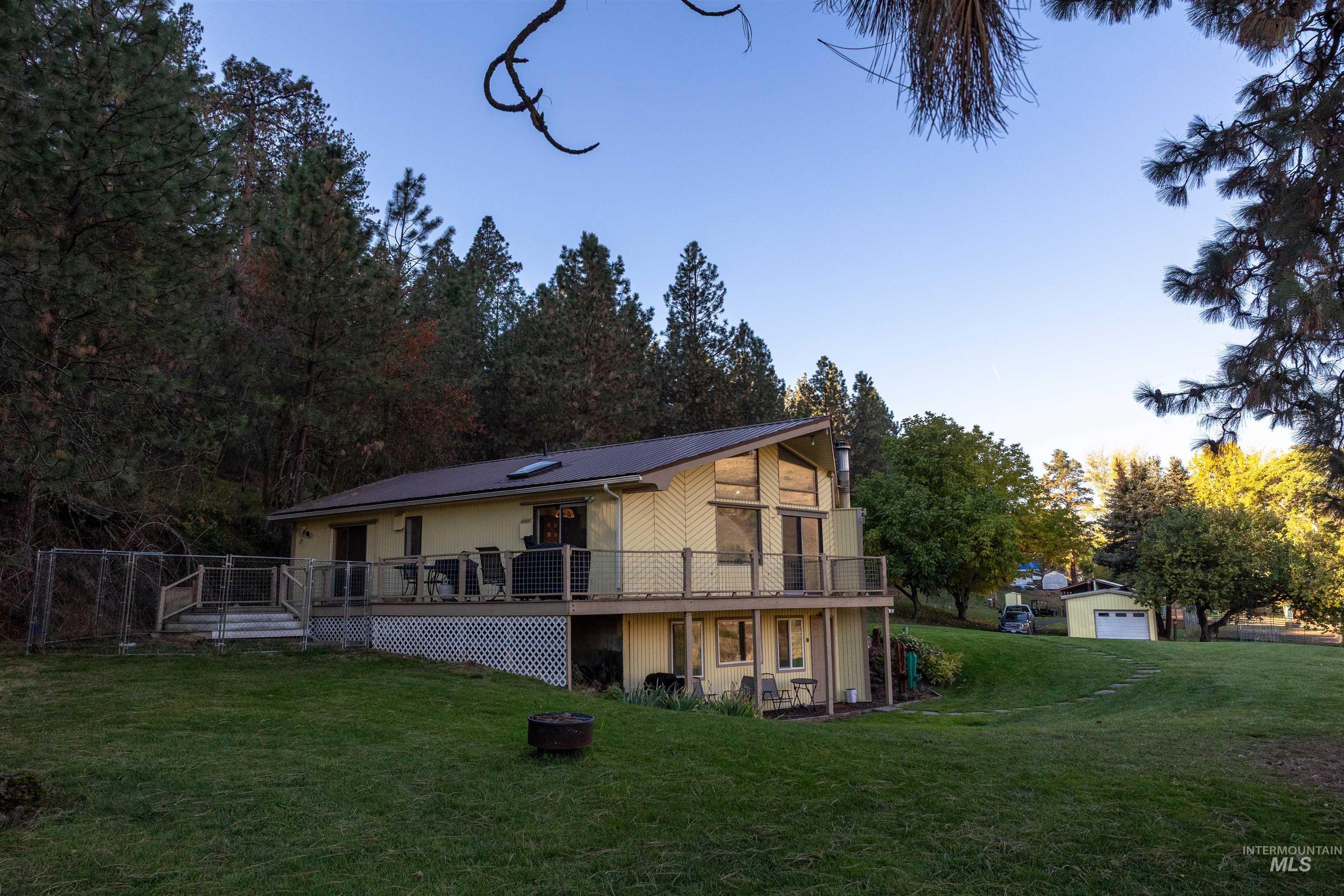 Back of house featuring a yard, a wooden deck, and a fire pit