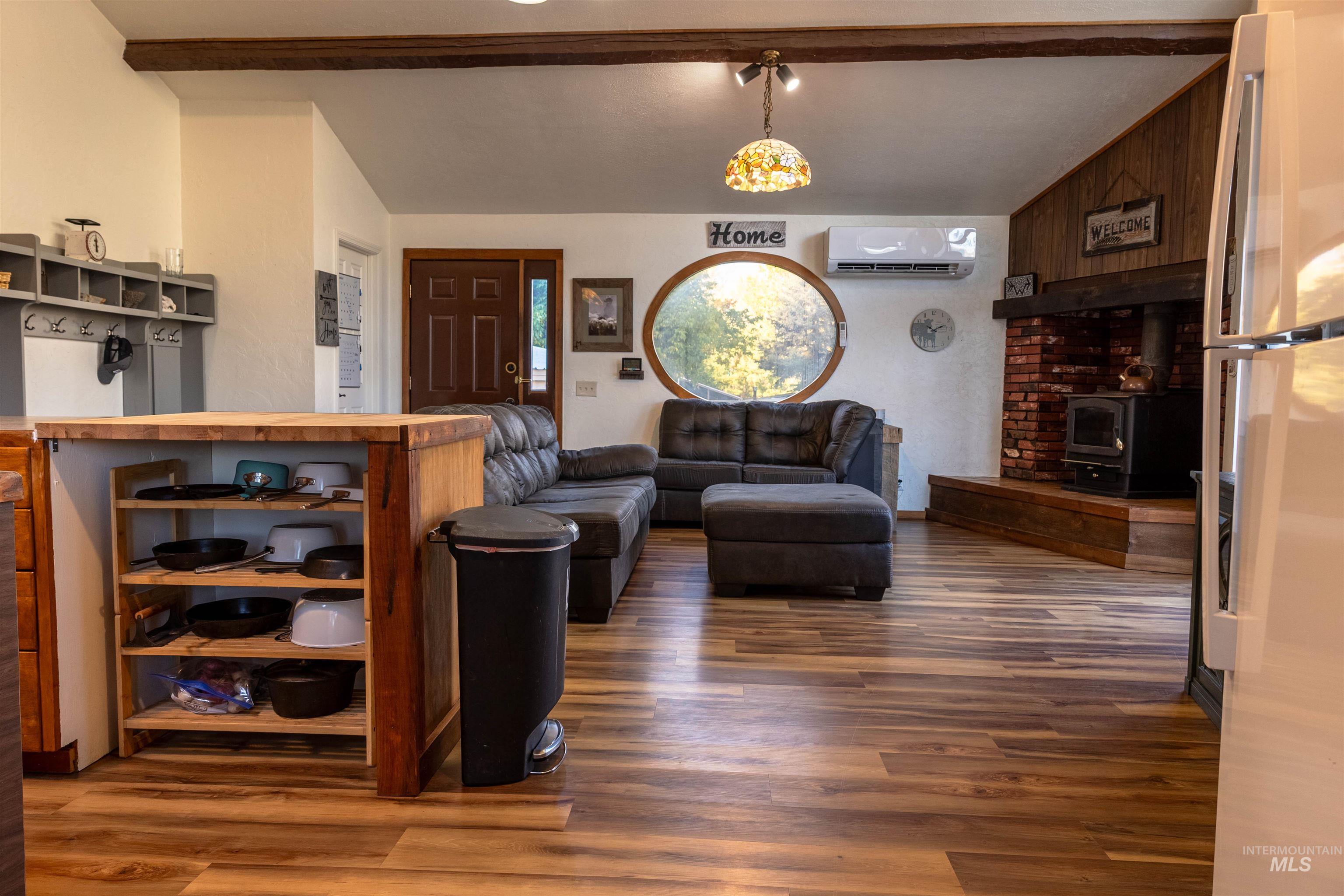 Living area with a wood stove, wood finished floors, and a wall unit AC