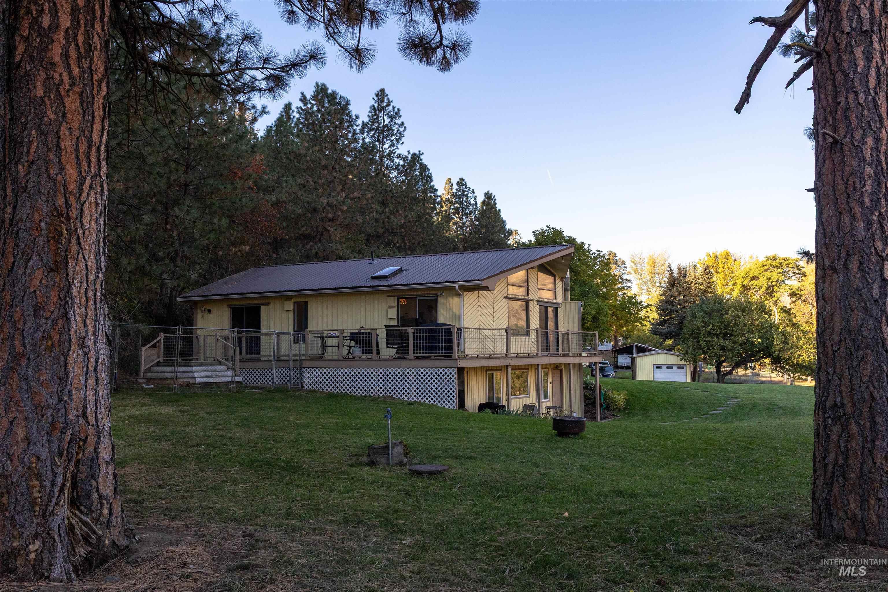Back of property with a yard, a deck, and a metal roof
