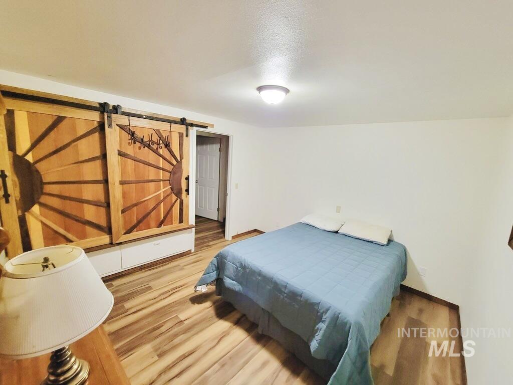 Bedroom with light wood-style flooring, a barn door, and a textured ceiling