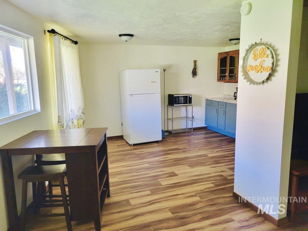Kitchen with freestanding refrigerator, light countertops, glass insert cabinets, dark wood-type flooring, and a textured ceiling
