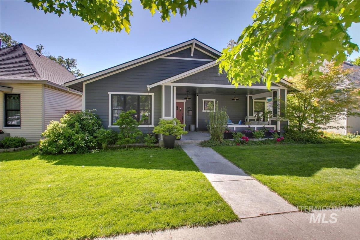 View of front of home with a porch, a front yard, and a ceiling fan