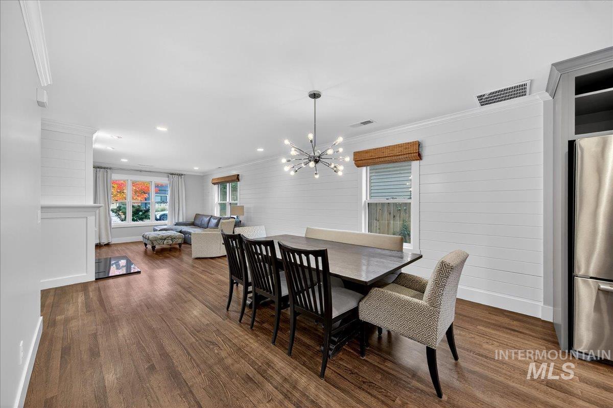 Dining area featuring ornamental molding, dark wood-type flooring, a chandelier, recessed lighting, and wood walls
