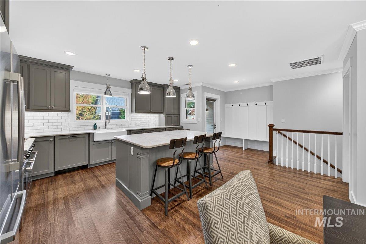Kitchen with gray cabinetry, a breakfast bar area, pendant lighting, a kitchen island, and dark wood-style flooring