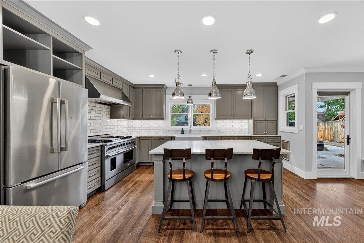 Kitchen with stainless steel appliances, gray cabinetry, a kitchen island, pendant lighting, and decorative backsplash