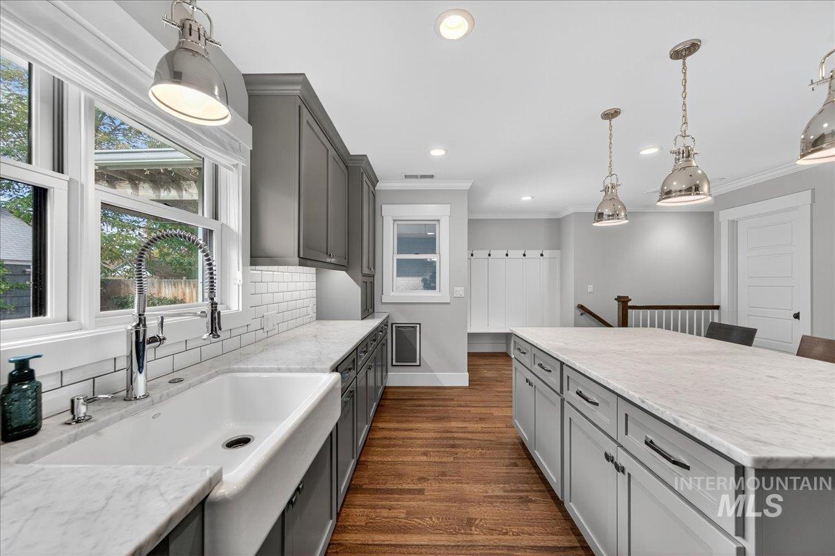 Kitchen featuring gray cabinets, hanging light fixtures, backsplash, dark wood finished floors, and ornamental molding