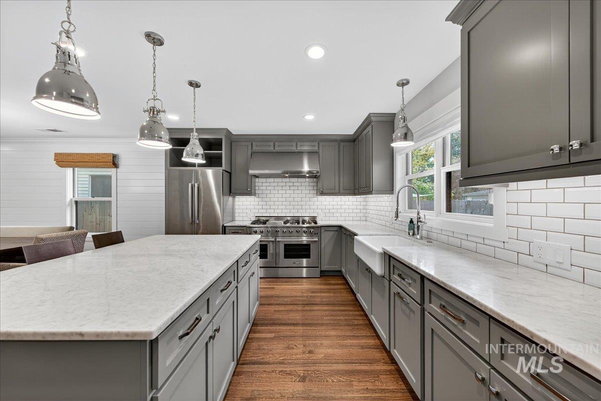 Kitchen featuring gray cabinets, a center island, high quality appliances, light stone counters, and recessed lighting