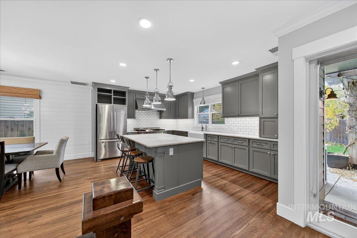 Kitchen with healthy amount of natural light, ornamental molding, gray cabinetry, pendant lighting, and a kitchen island