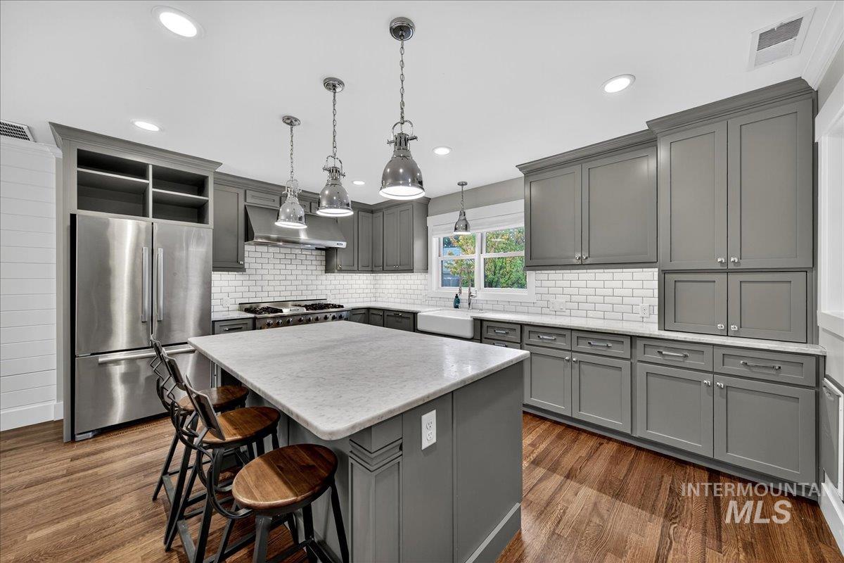 Kitchen with gray cabinets, freestanding refrigerator, dark wood-style flooring, a kitchen island, and open shelves