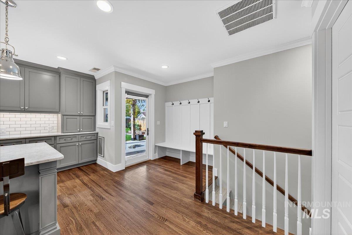 Kitchen with gray cabinetry, backsplash, dark wood-type flooring, ornamental molding, and pendant lighting