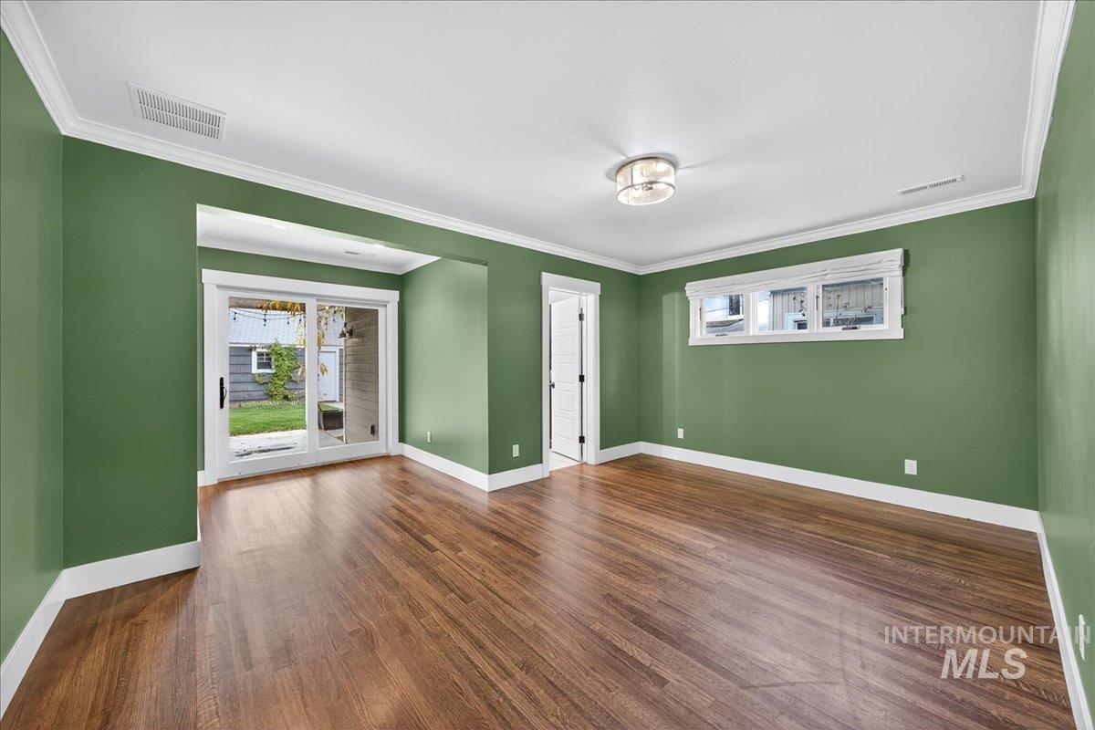 Unfurnished room featuring ornamental molding and dark wood finished floors