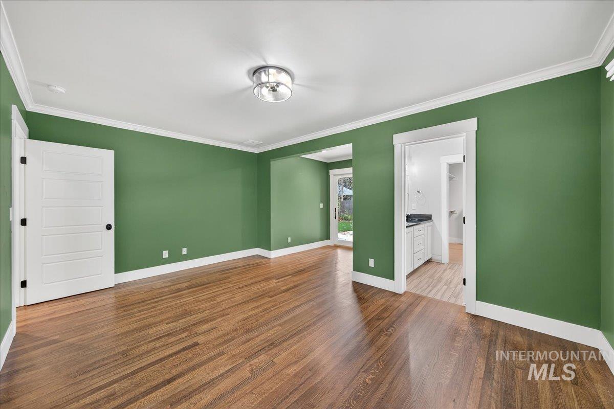 Spare room featuring crown molding and dark wood-type flooring